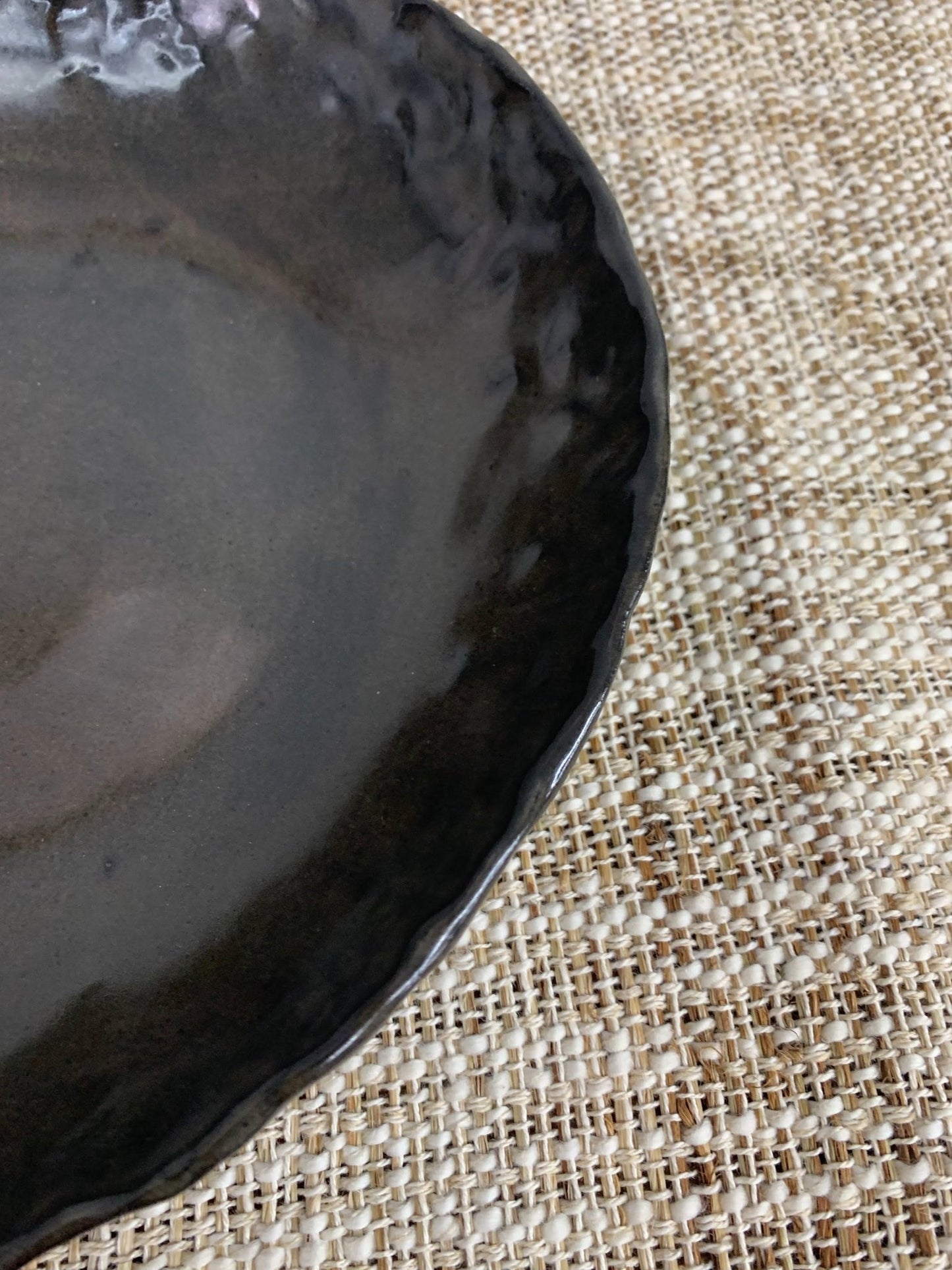 Black ceramic plate on a textured beige surface