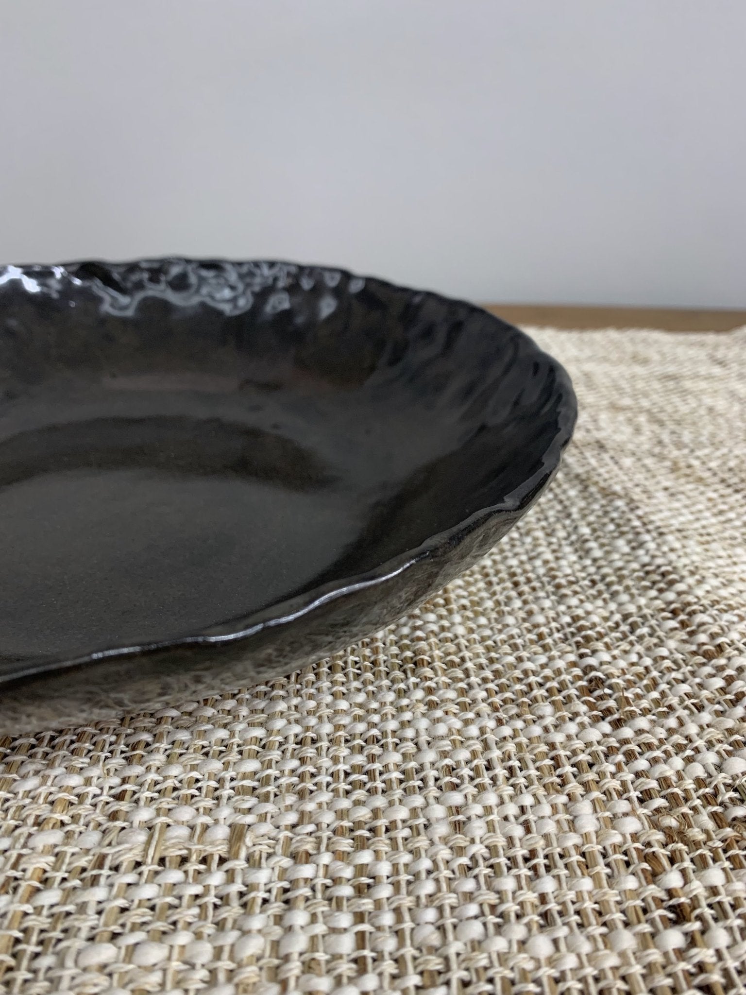 Black ceramic plate on a textured woven surface
