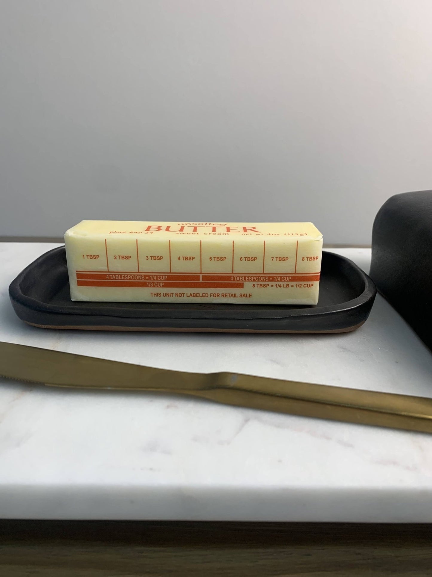 Black handmade ceramic butter dish on marble surface