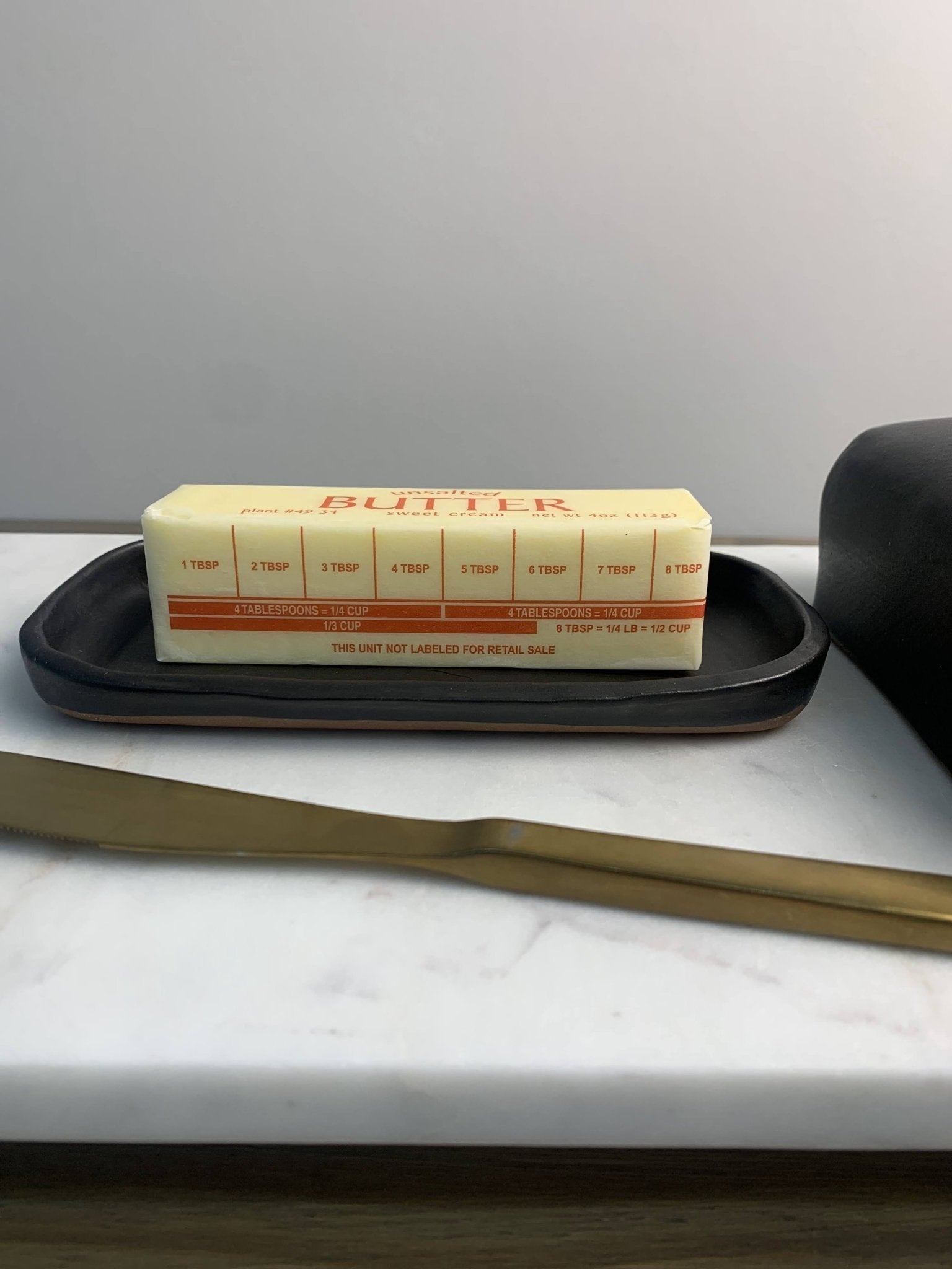Black handmade ceramic butter dish on marble surface