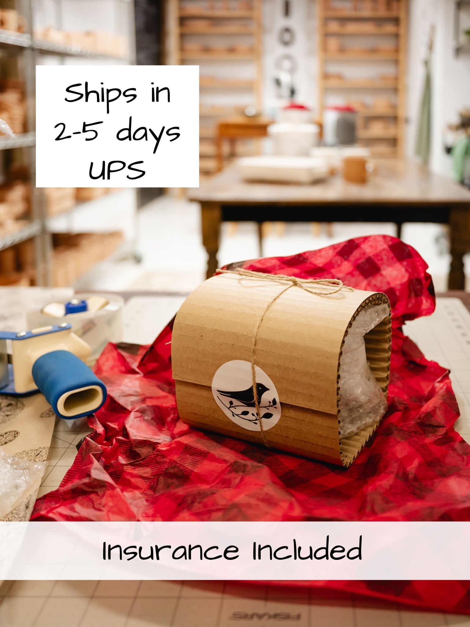 a package wrapped in bubble wrap and cardboard with red tissue paper next to shipping tools on a table