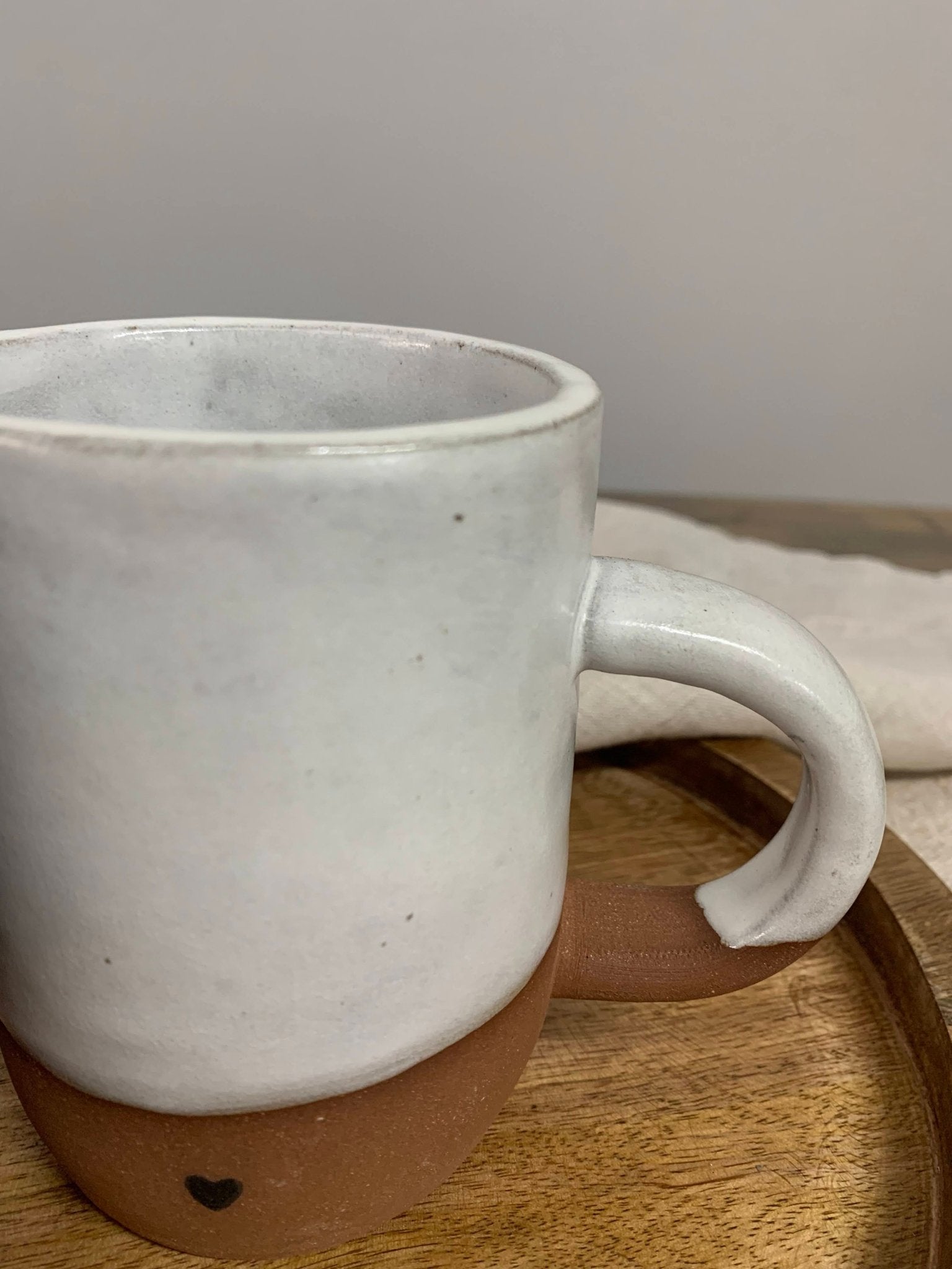 White ceramic mug with brown base on a wooden surface