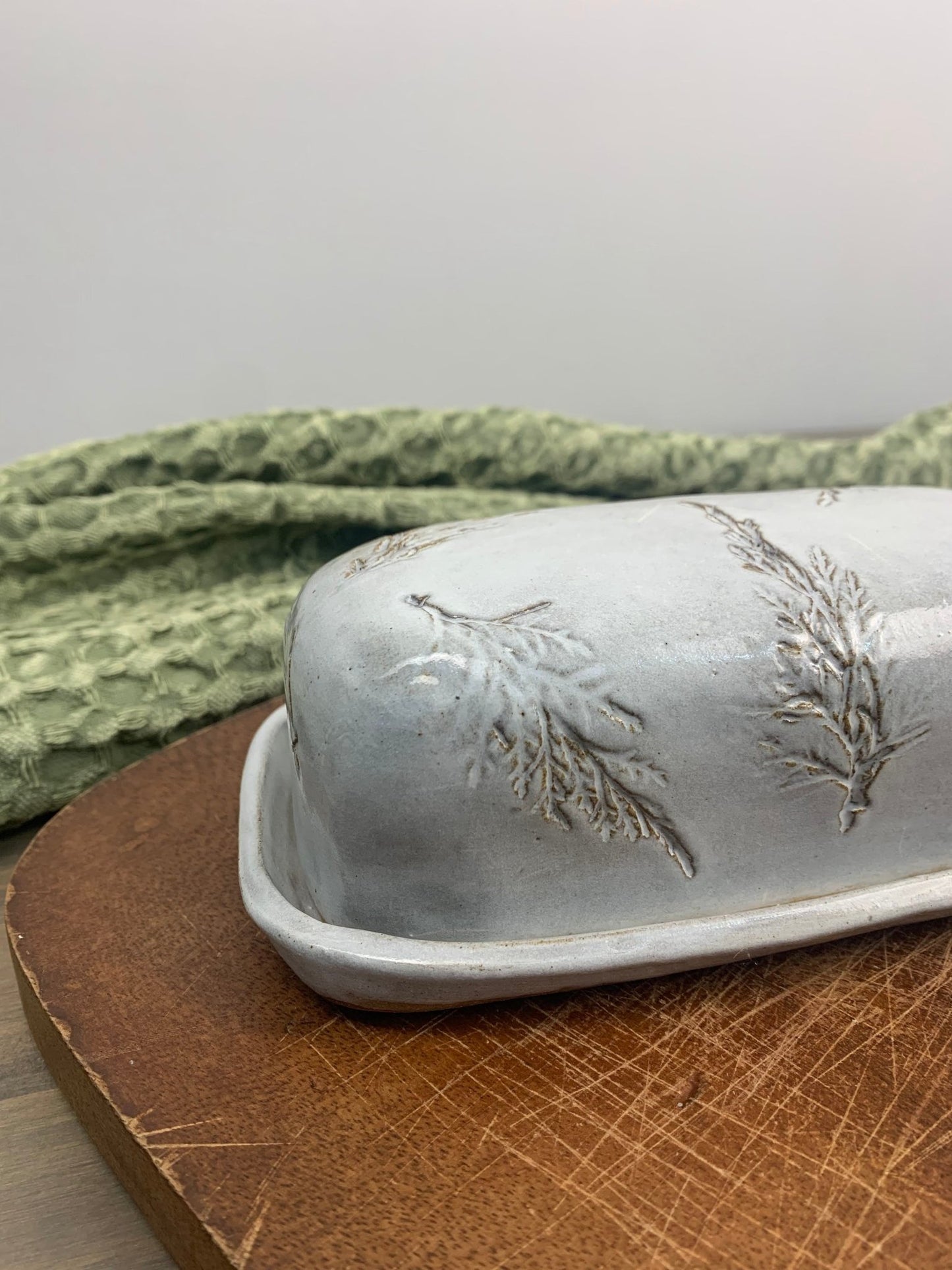handcrafted butterdish on wood cutting board with green tea towel