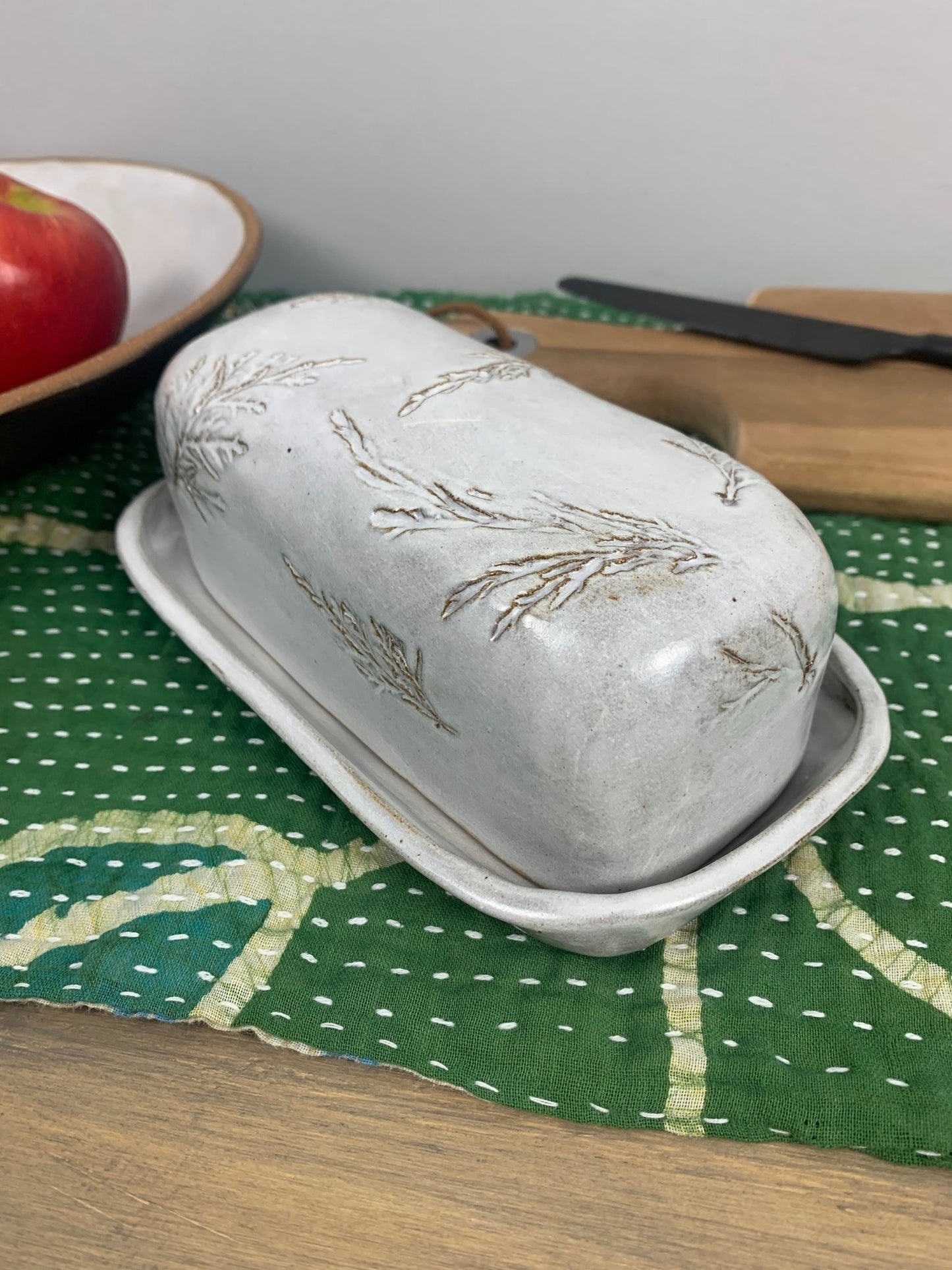 handcrafted butter dish with pine needle patterns on a green cloth