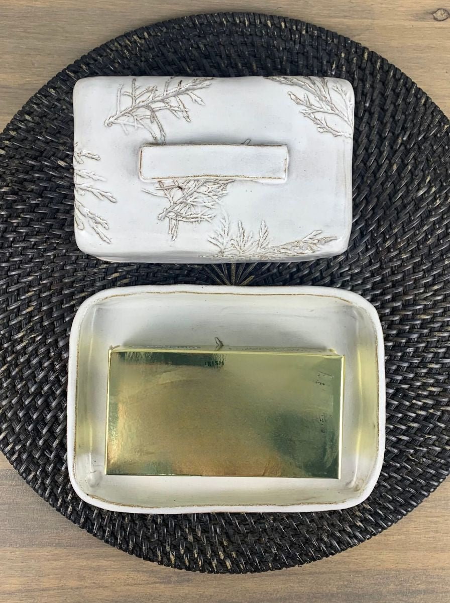 an open butter dish with a large european size butter package in the bottom tray