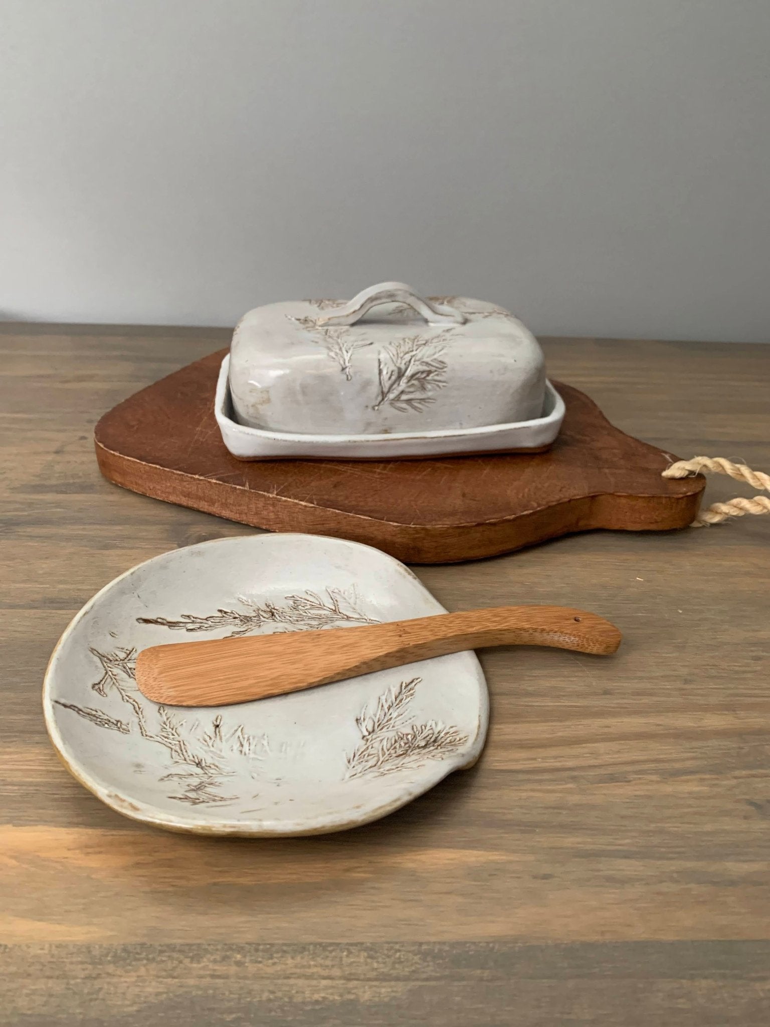 handcrafted Ceramic butter dish with wooden spreader on a wooden surface