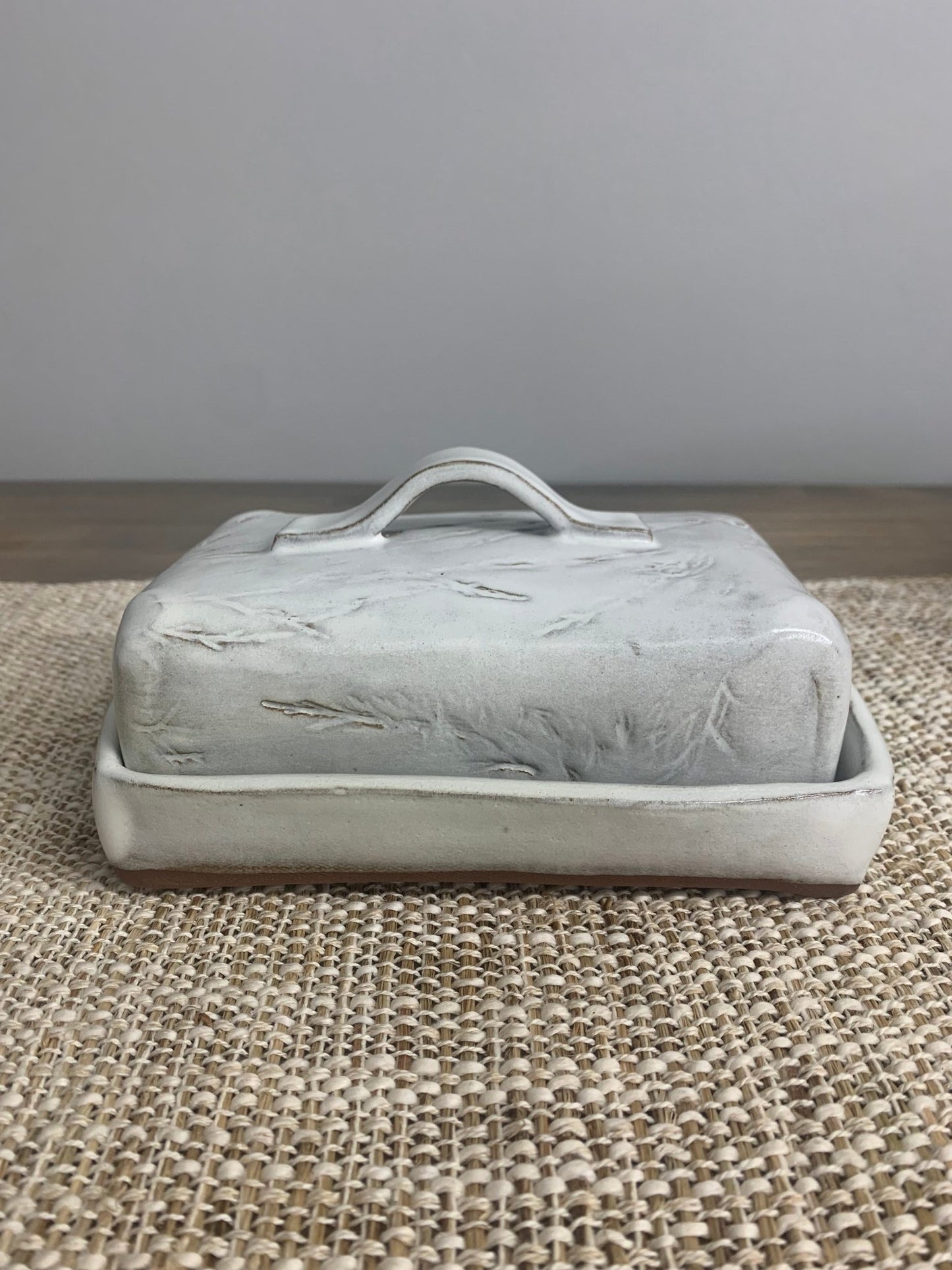 handmade ceramic butter dish with lid on a textured surface