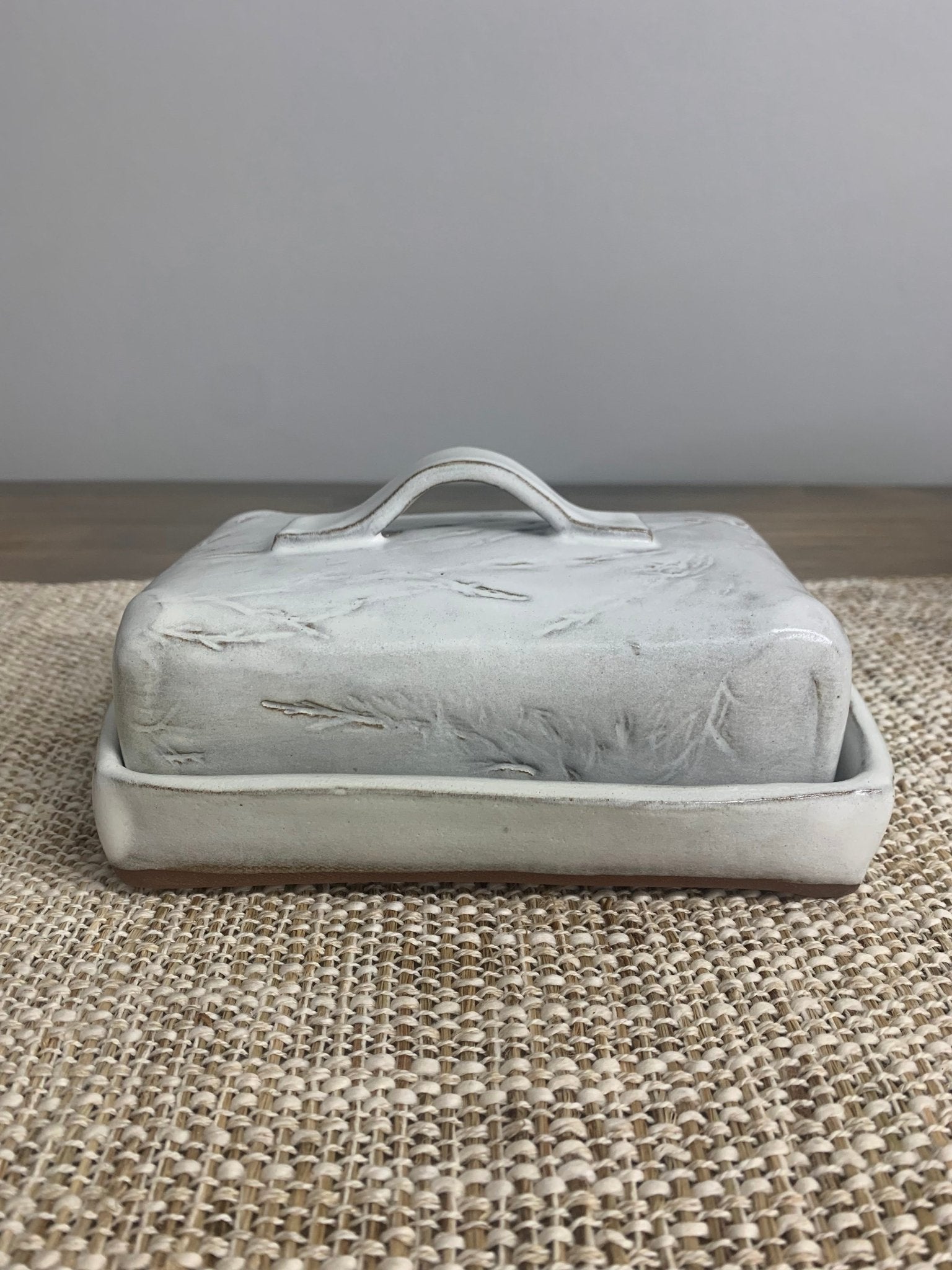 handmade ceramic butter dish with lid on a textured surface