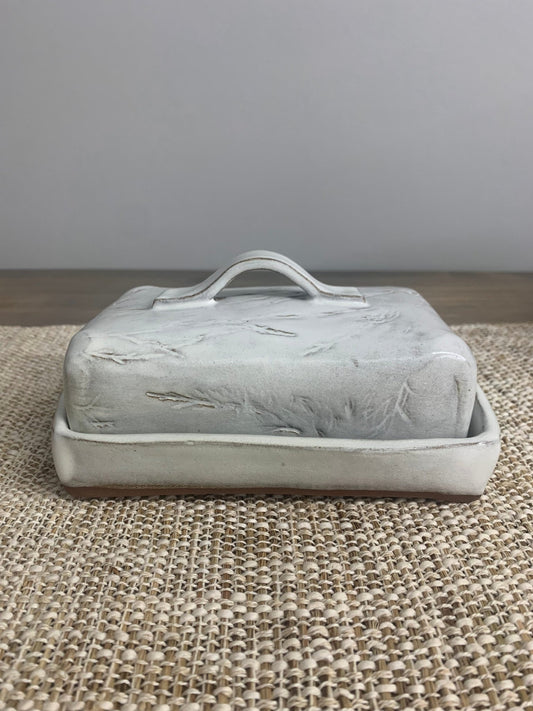 handmade ceramic butter dish with lid on a textured surface