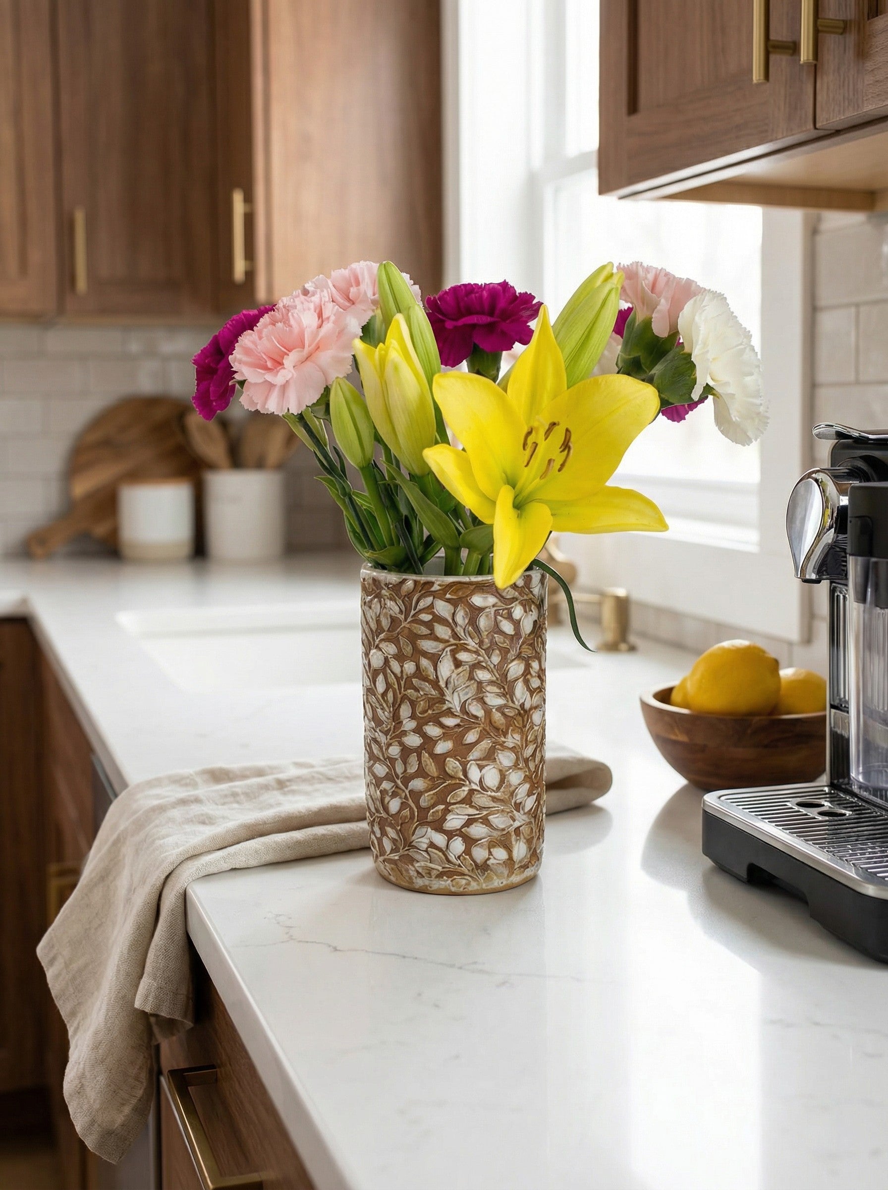 rustic handcrafted cylindrical Vase with colorful flowers on a kitchen counter