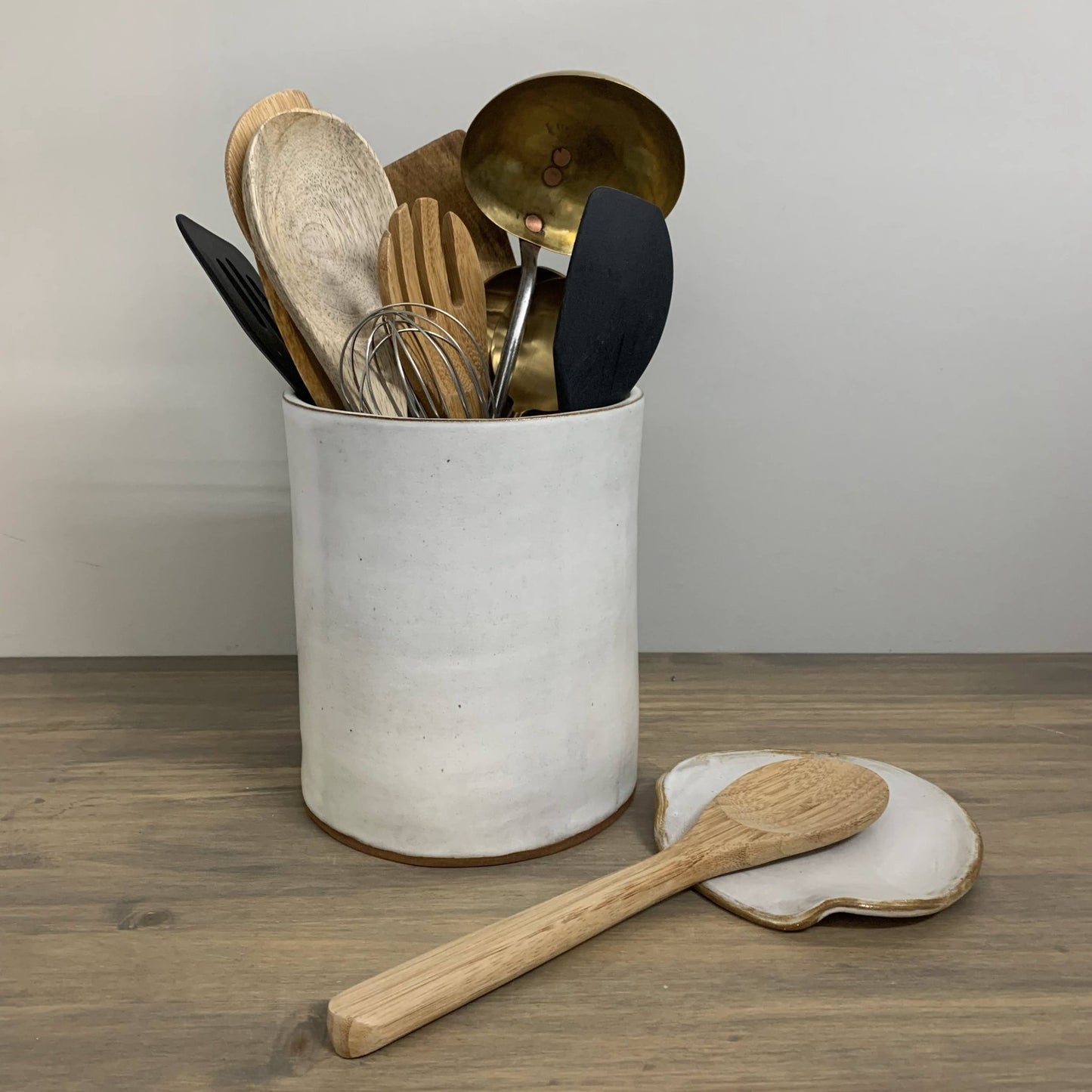White container with kitchen utensils on a wooden surface