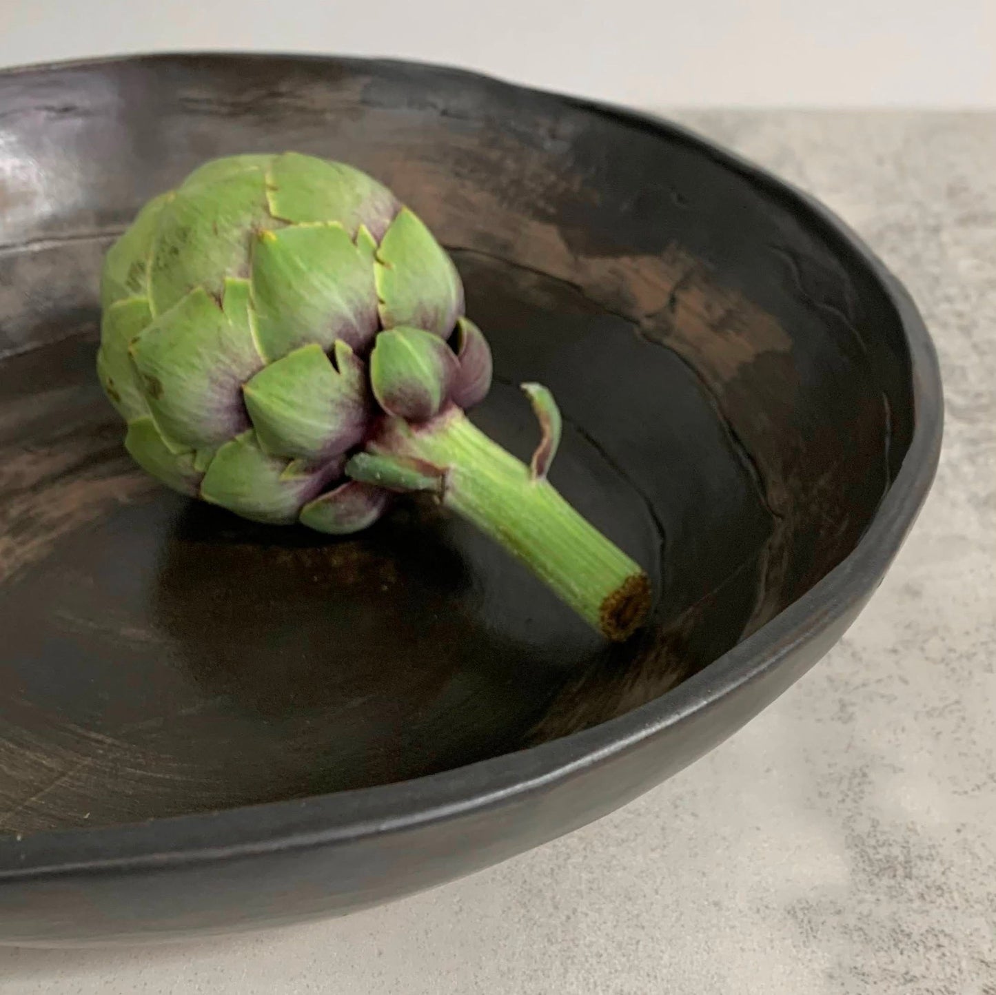 Artichoke on a dark ceramic plate with a light background