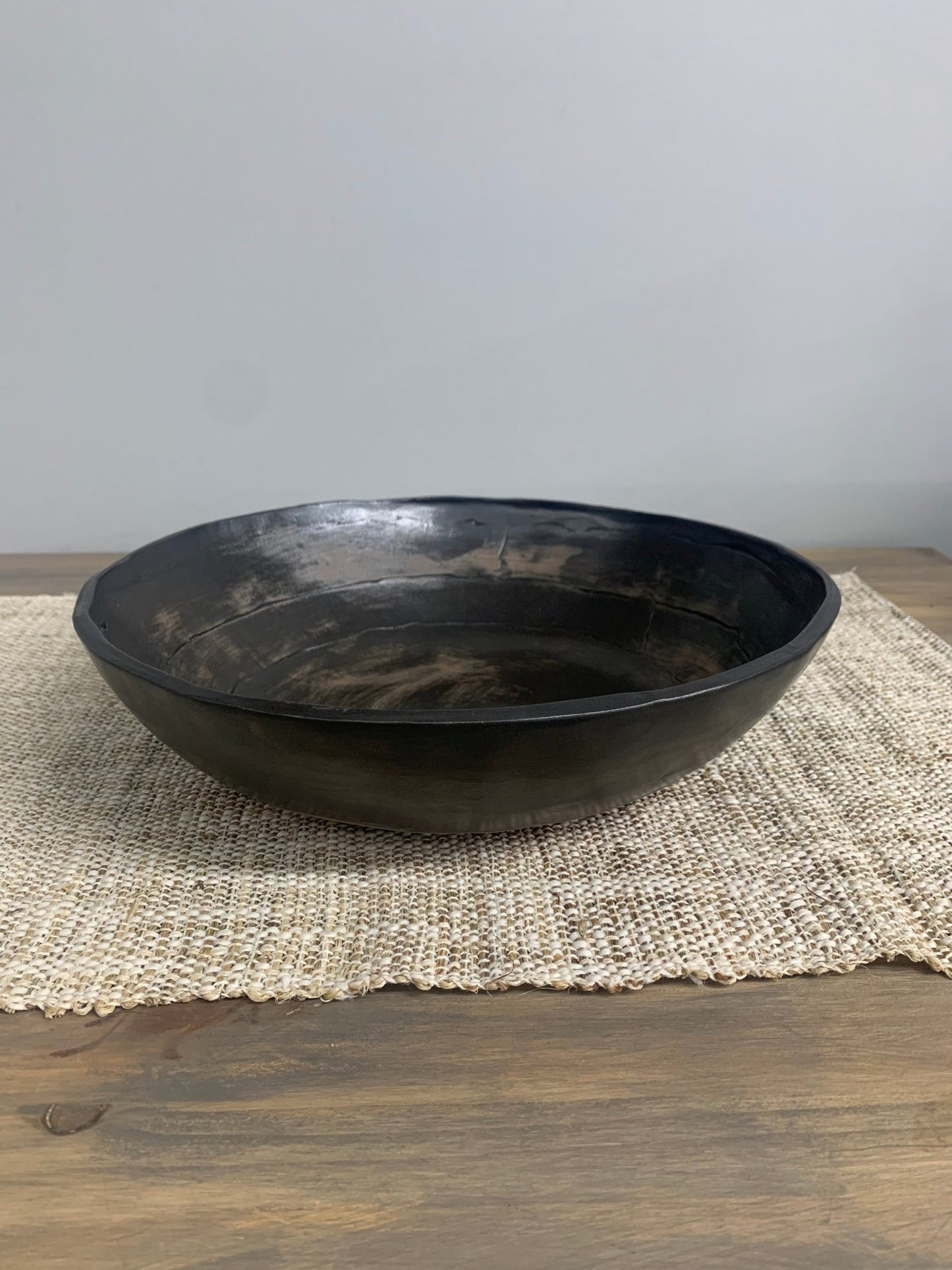 Black ceramic bowl on a textured placemat with a neutral background