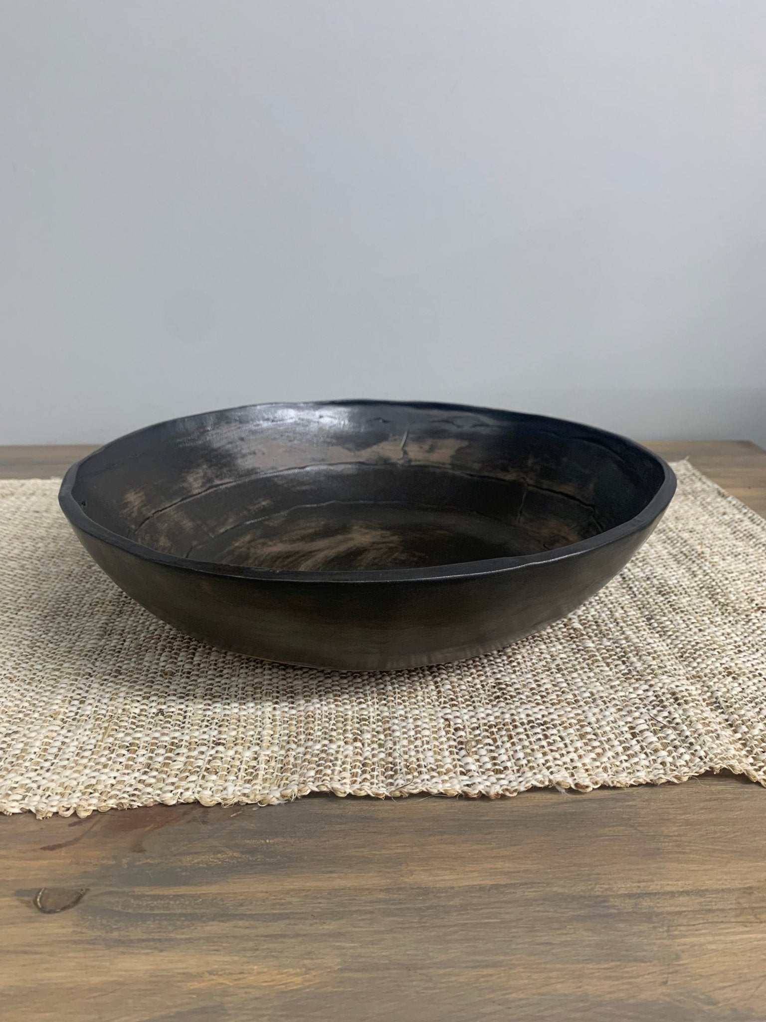Black ceramic bowl on a textured placemat with a neutral background