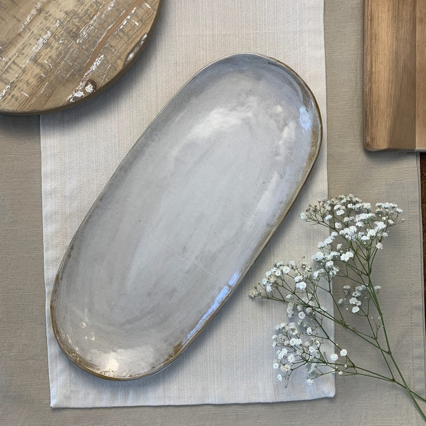 Oval ceramic dish on a textured surface with a small plant.