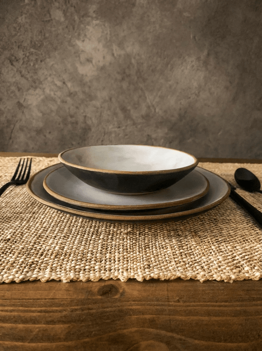 Set of artisan plates and bowl on a textured surface with a neutral background