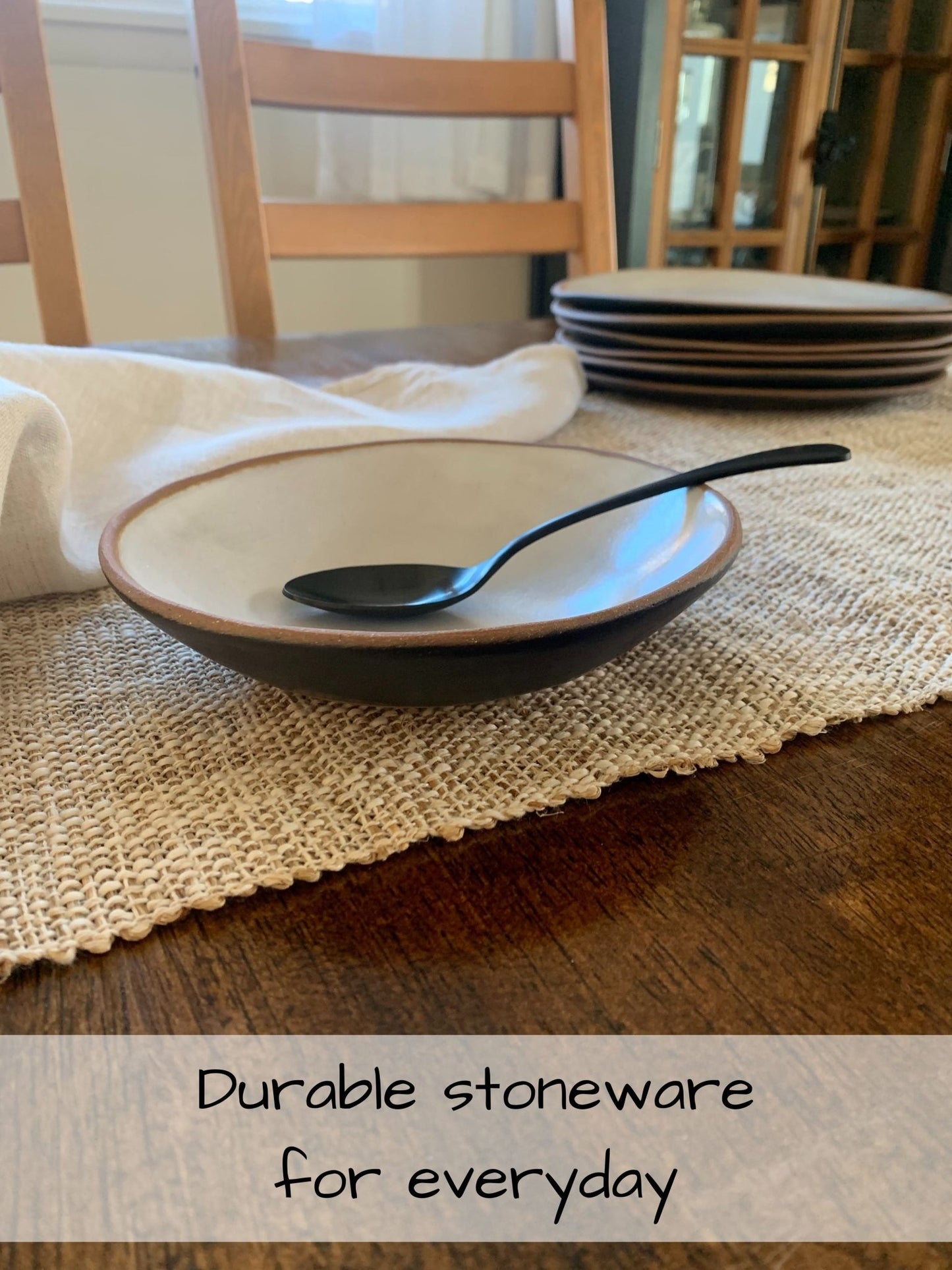 Stoneware bowl with spoon on a table with text 'Durable stoneware for everyday'.