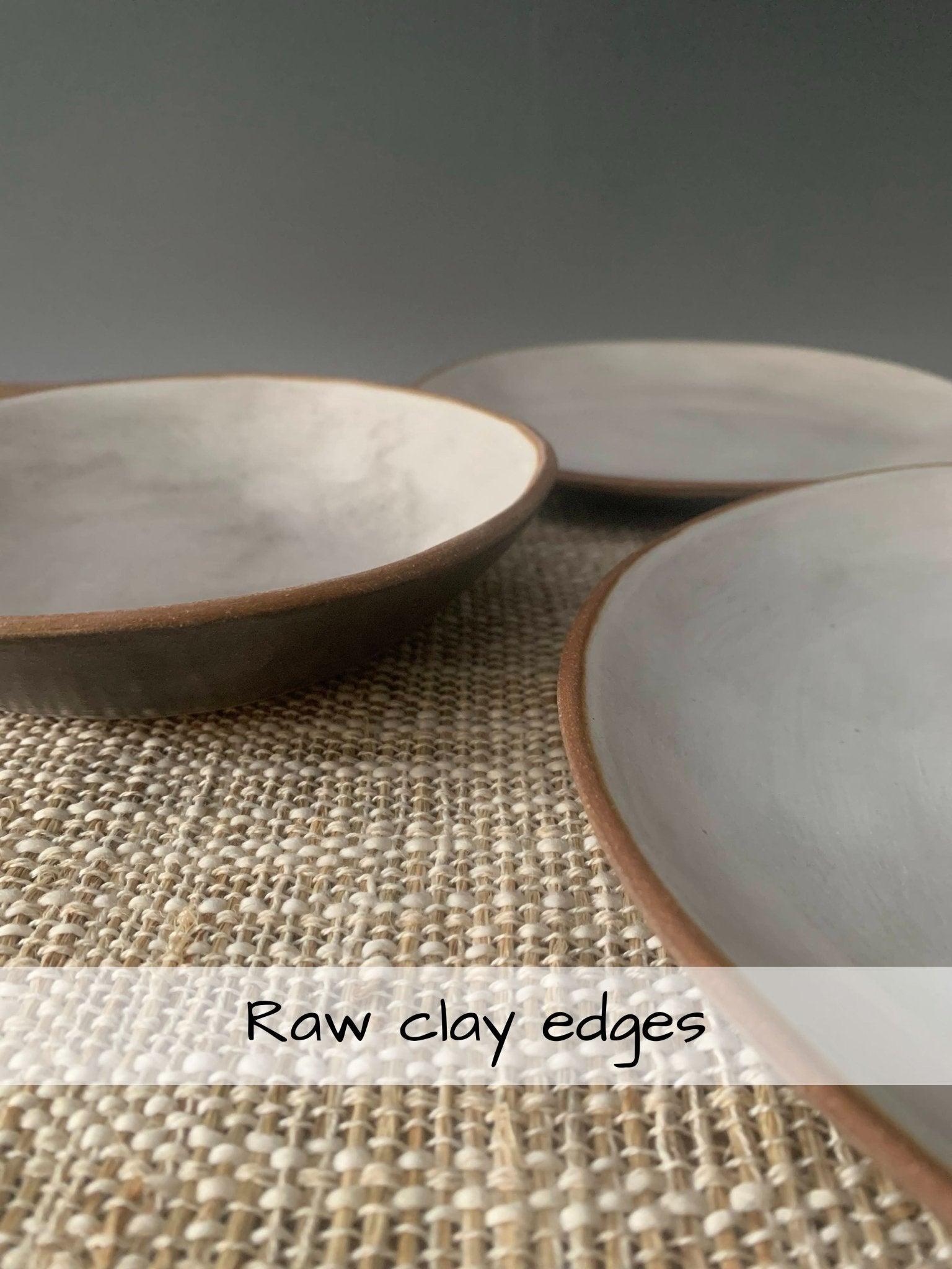 Three ceramic bowls with raw clay edges on a textured surface.