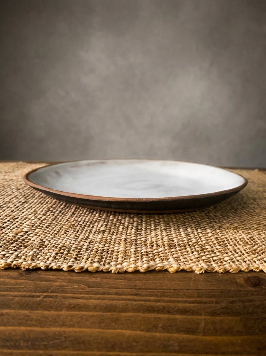 handmade Ceramic plate on a textured placemat with a gray background