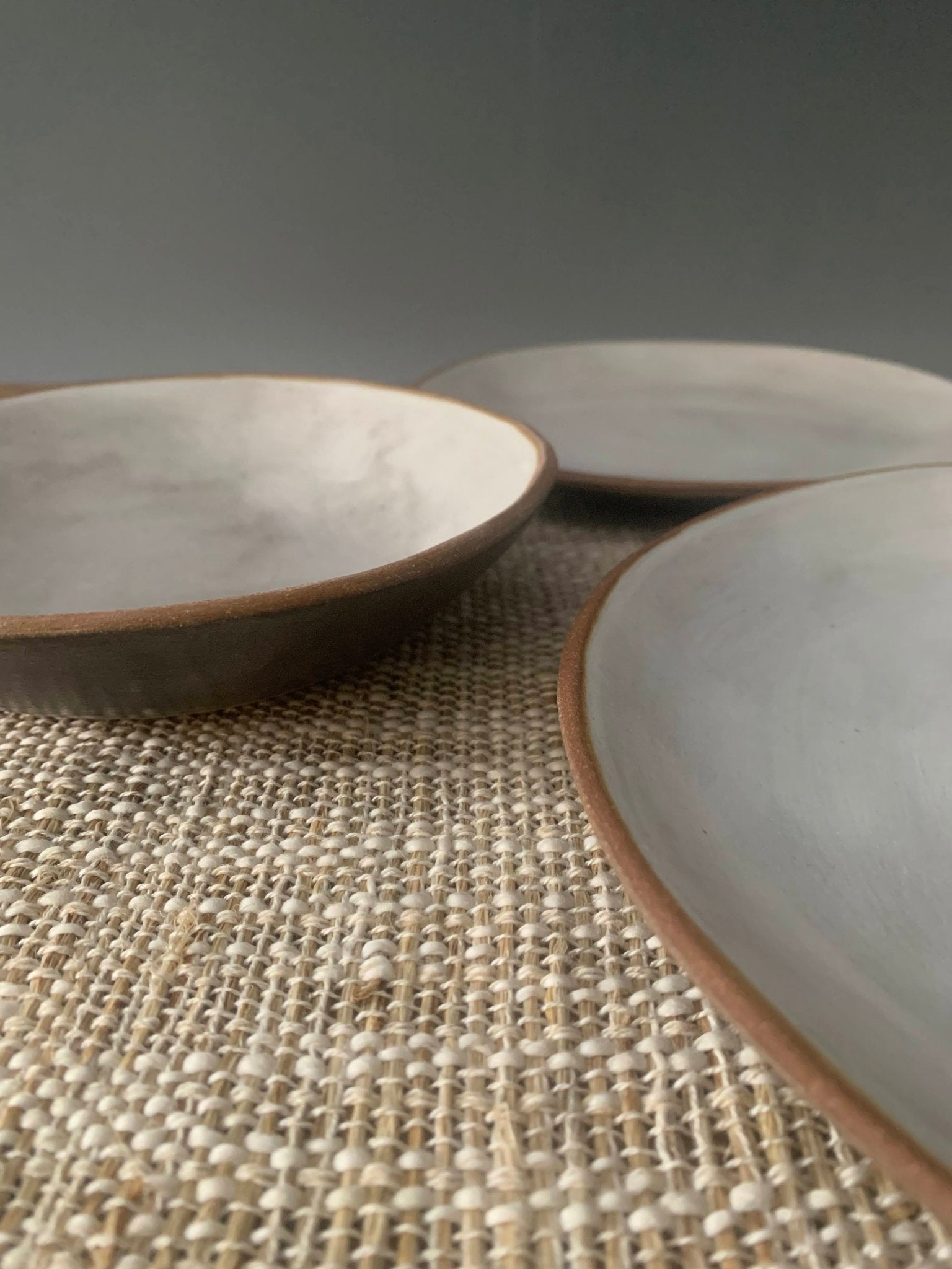Three handmade  ceramic bowls on a textured surface with a gray background