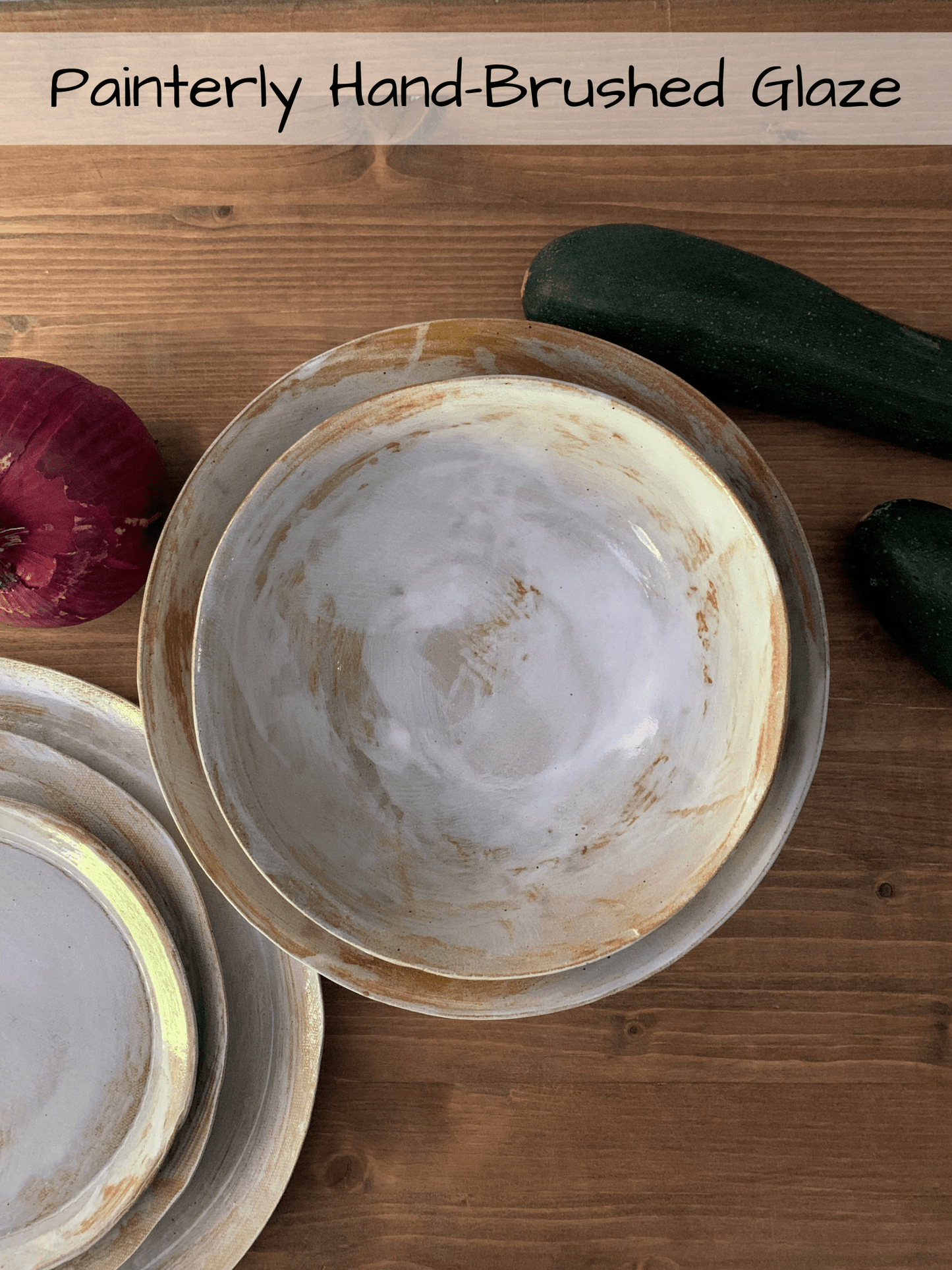 Three ceramic bowls with a painterly hand-brushed glaze on a wooden surface.