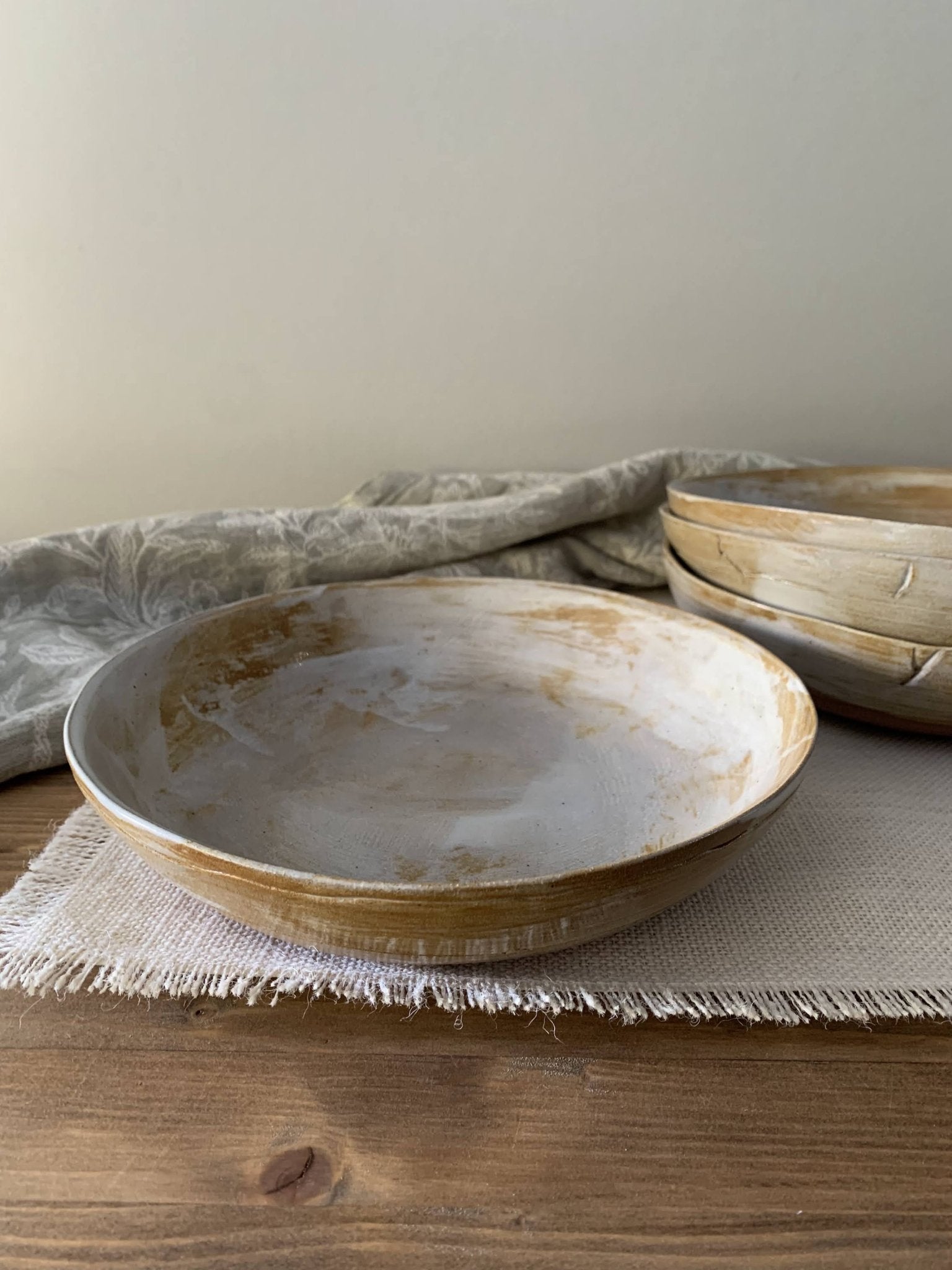 Set of handmade ceramic plates on a wooden surface with a neutral background