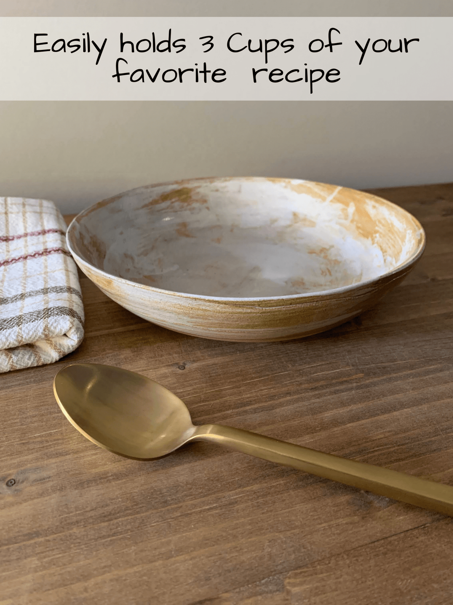 Large handmade ceramic bowl and gold spoon on a wooden surface with text about capacity.