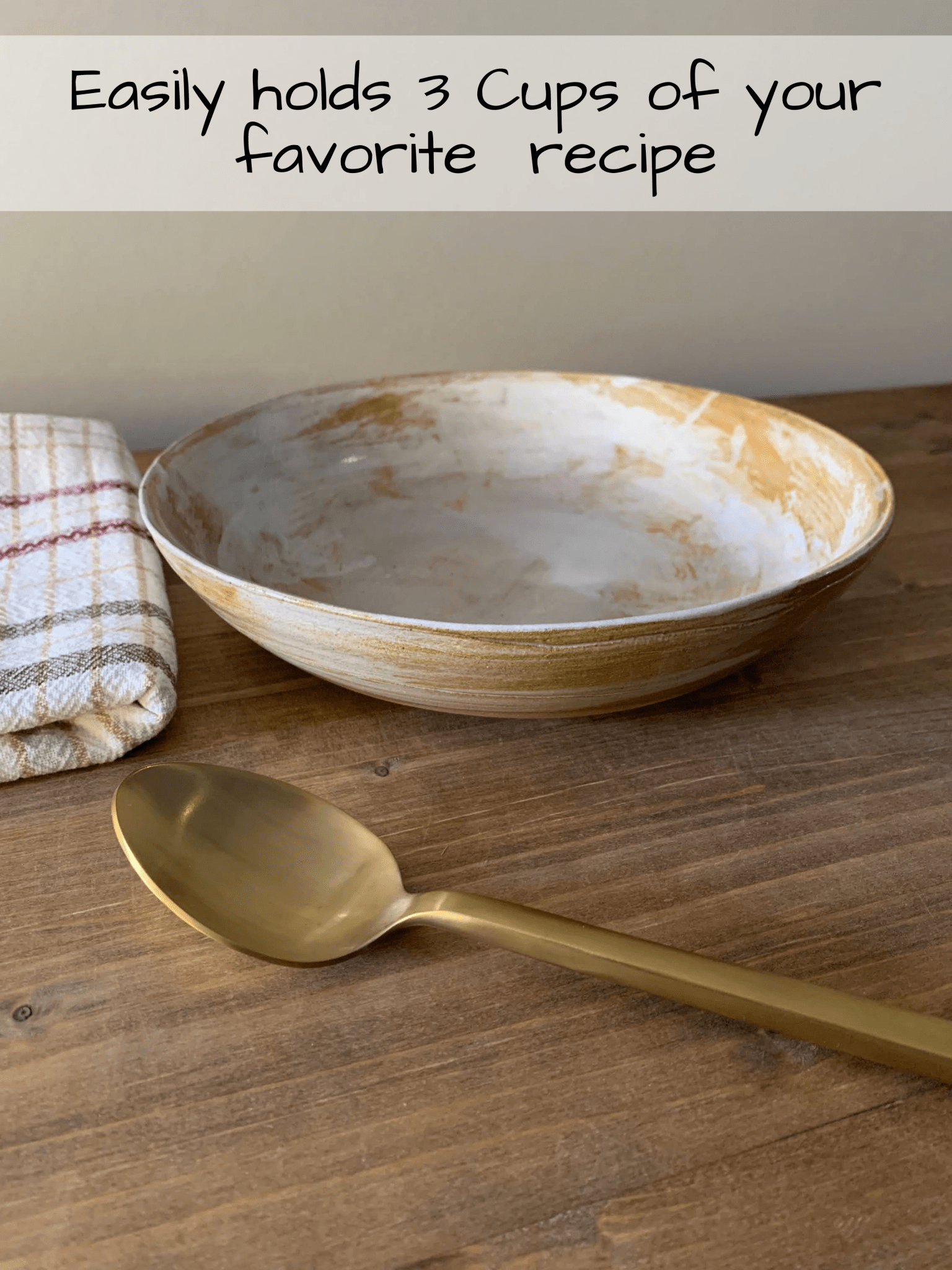 Large handmade ceramic bowl and gold spoon on a wooden surface with text about capacity.