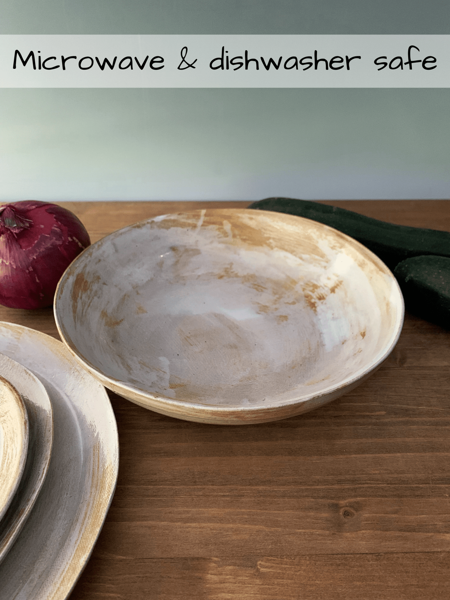Handmade ceramic bowl on a wooden surface with text indicating microwave and dishwasher safety.