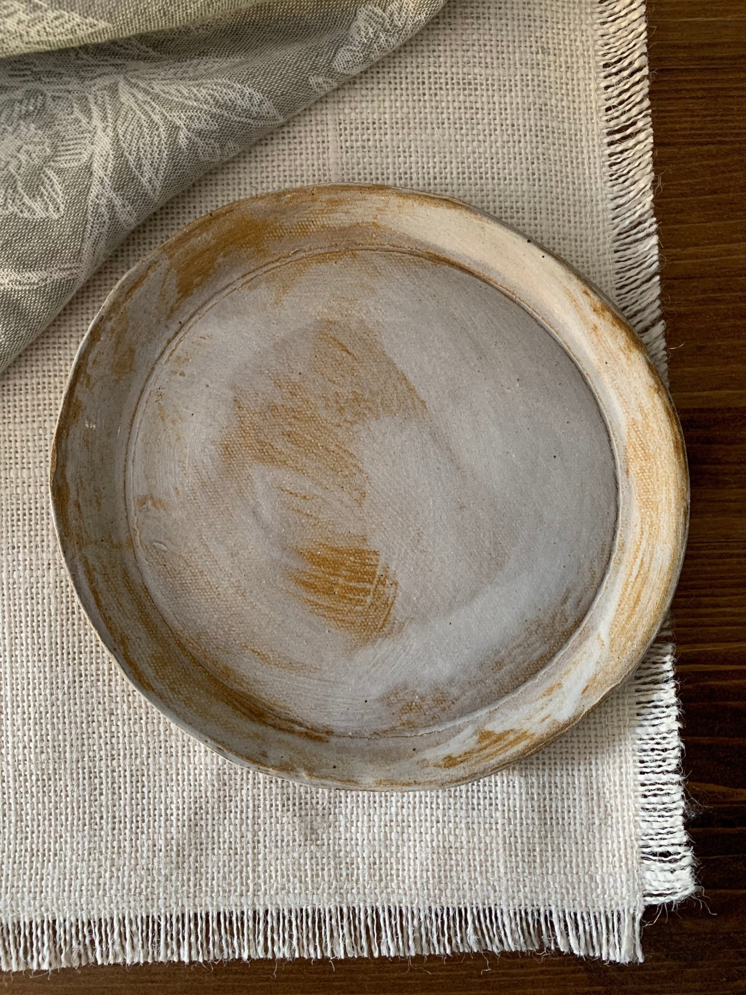 Round handmade ceramic plate on a textured fabric surface