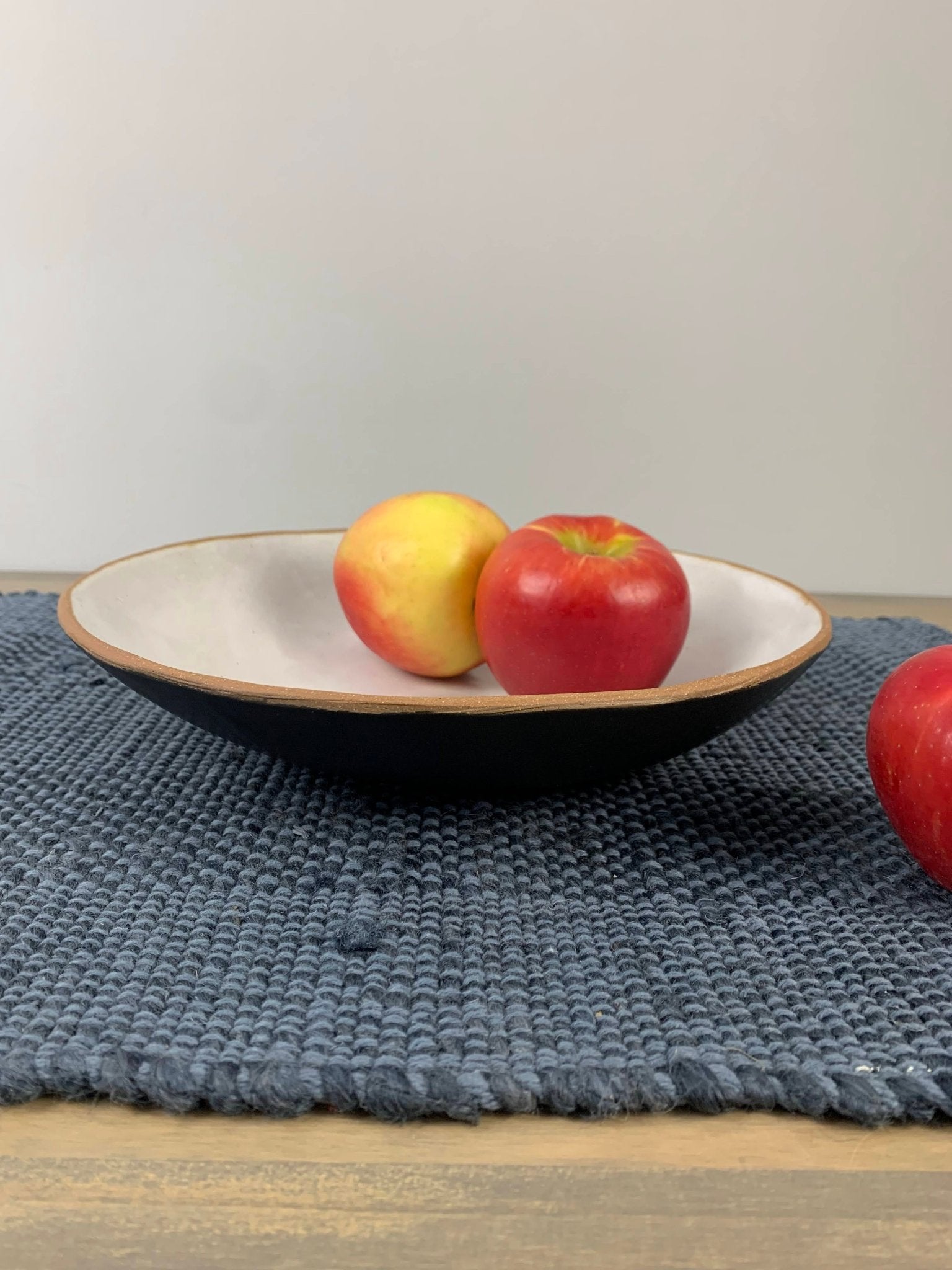 stoneware fruit Bowl with apples on a textured blue placemat