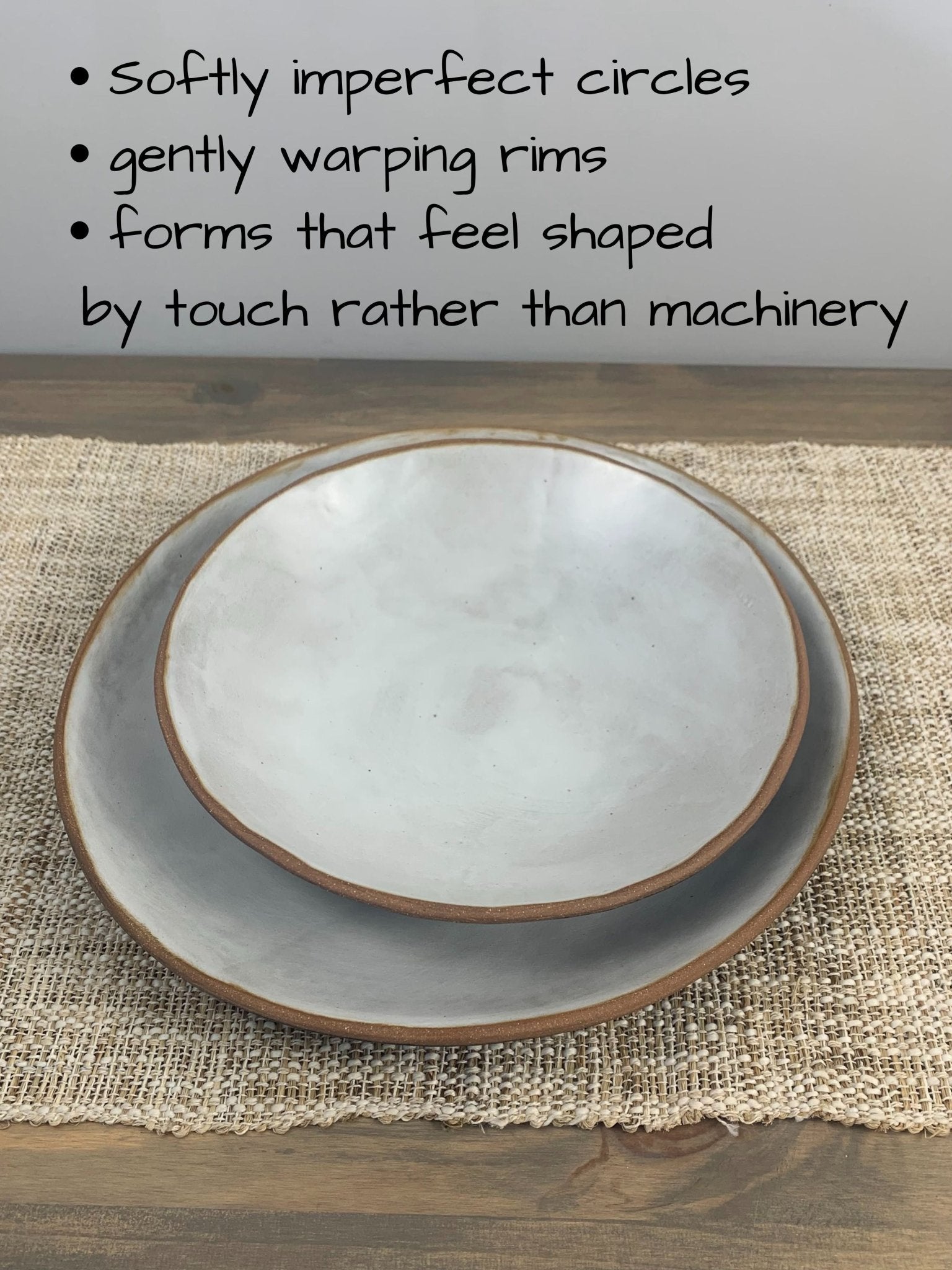 Stack of 2 ceramic shallow bowls with satin surface and brown raw clay edges on a woven mat