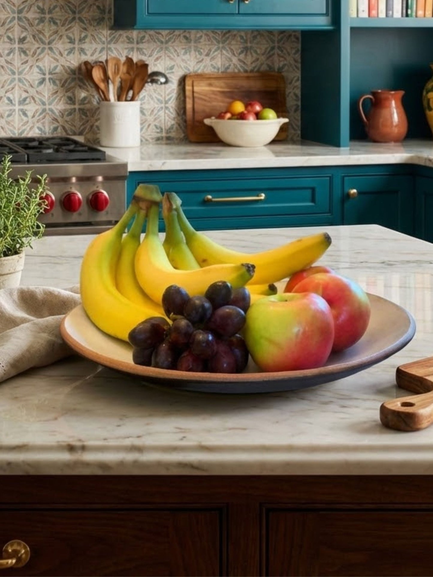 handmade pottery Fruit bowl with bananas, grapes, and apples on a kitchen counter