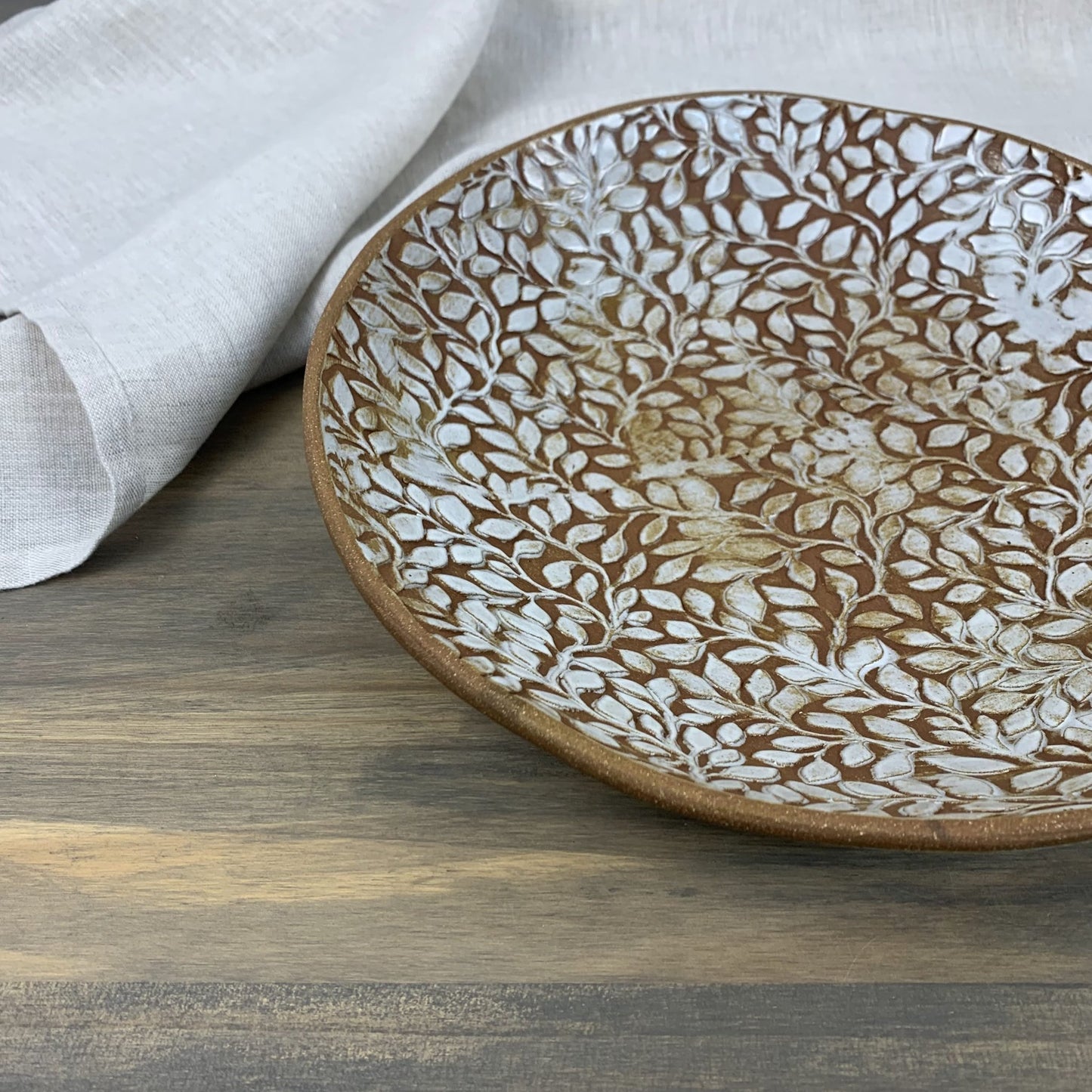 Ceramic plate with leaf pattern on a wooden surface