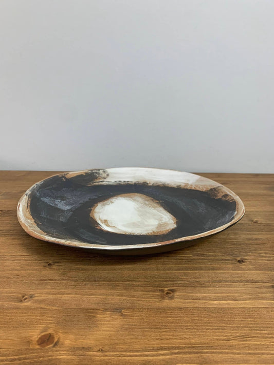 Handmade pottery plate with a natural, rustic finish on a wooden surface