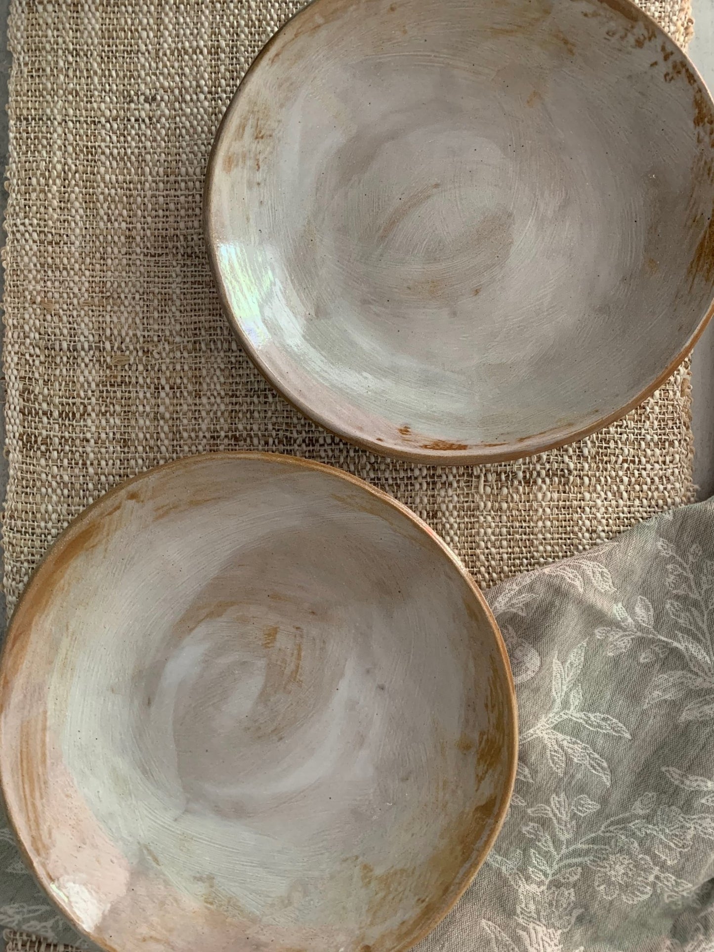 Two handmade ceramic bowls with a textured surface on a woven mat