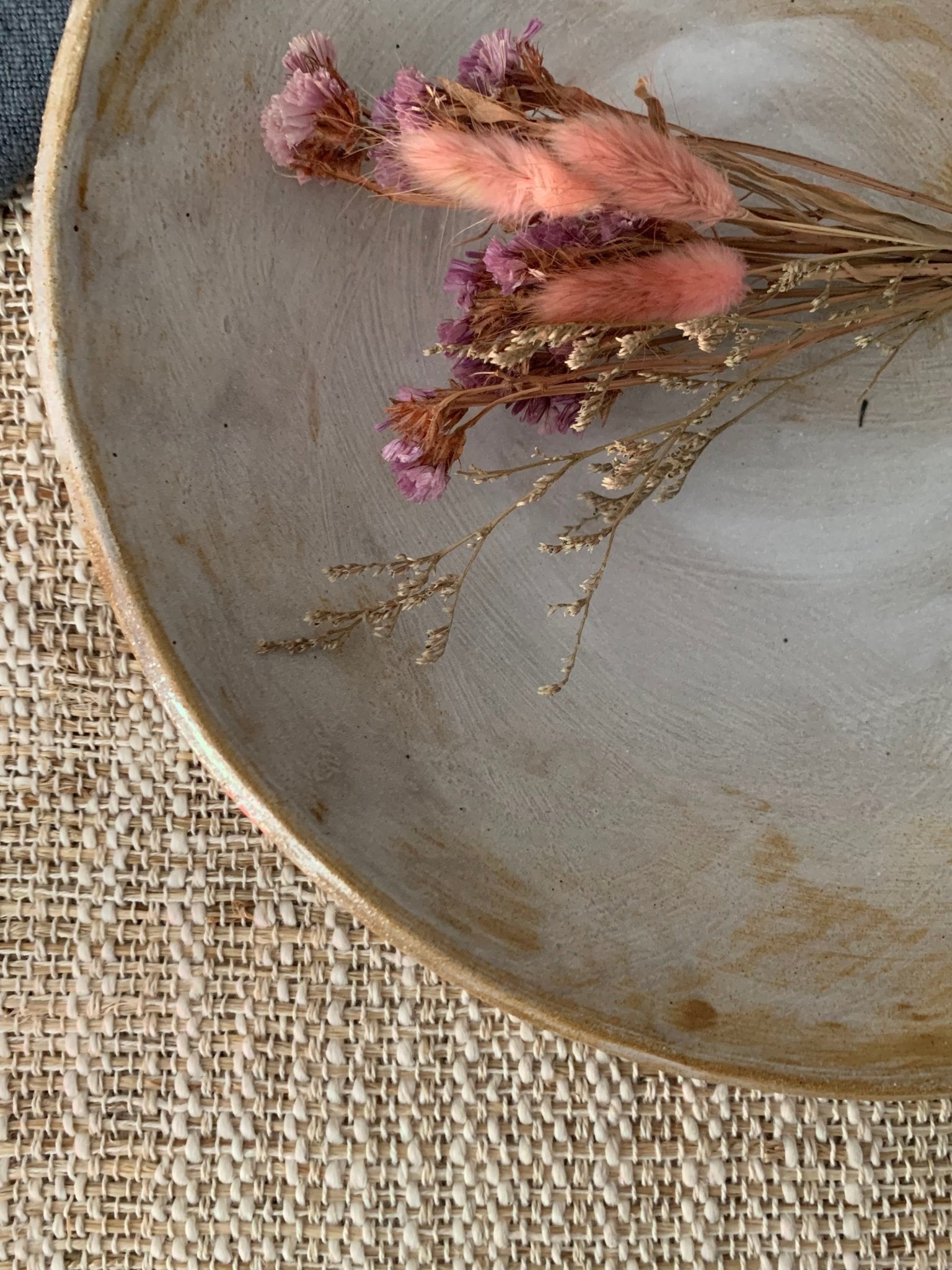 Dried flowers on a textured ceramic plate with a burlap background