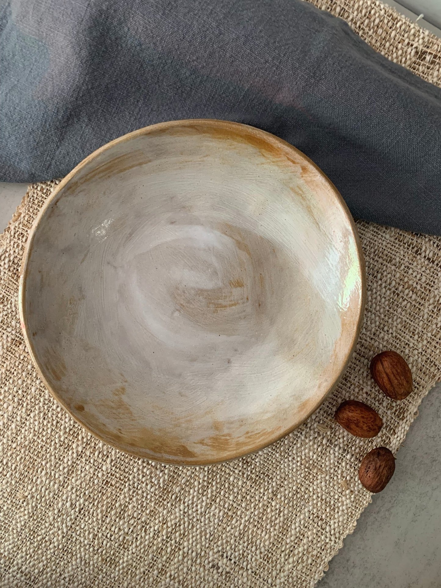 Handmade ceramic bowl on a textured surface with nuts