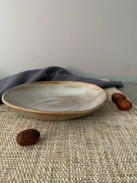 Ceramic handmade plate on a textured surface with a neutral background