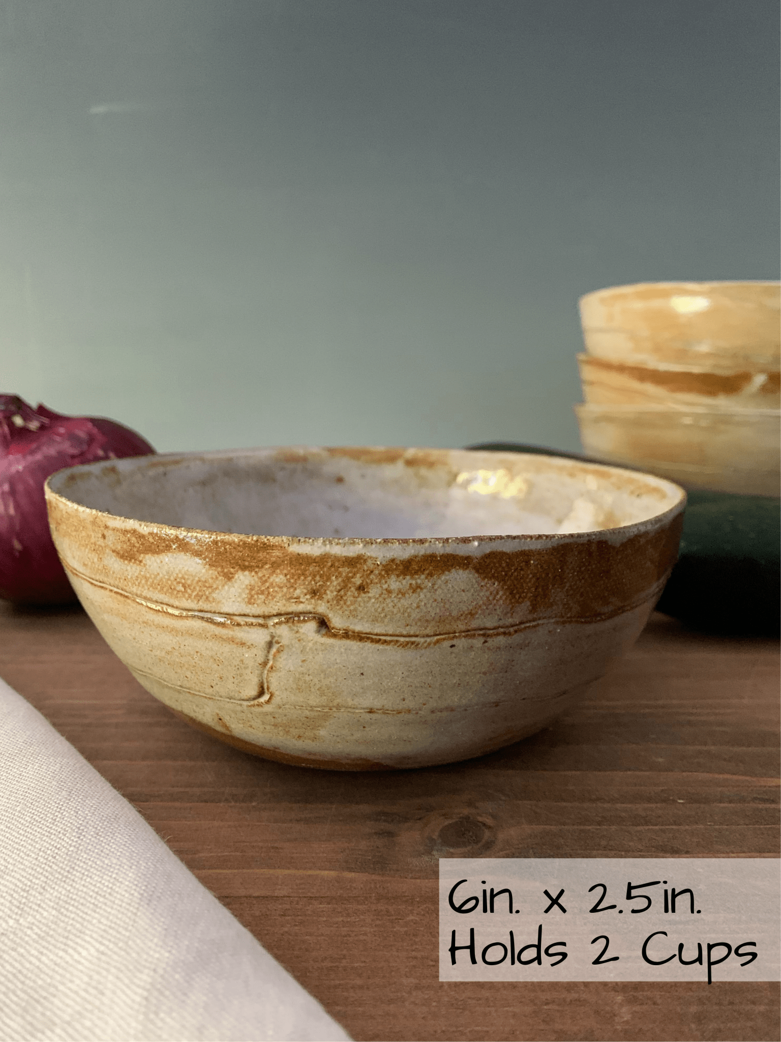 Ceramic handmade bowl on a wooden surface with text indicating size and capacity.