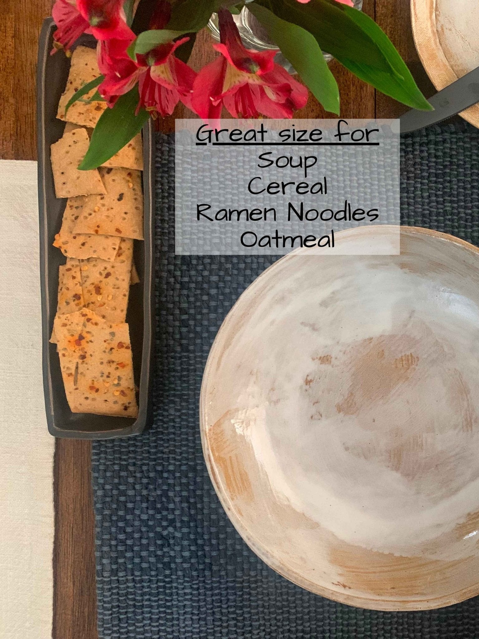 Crackers on a stoneware tray with a bowl and flowers on a table