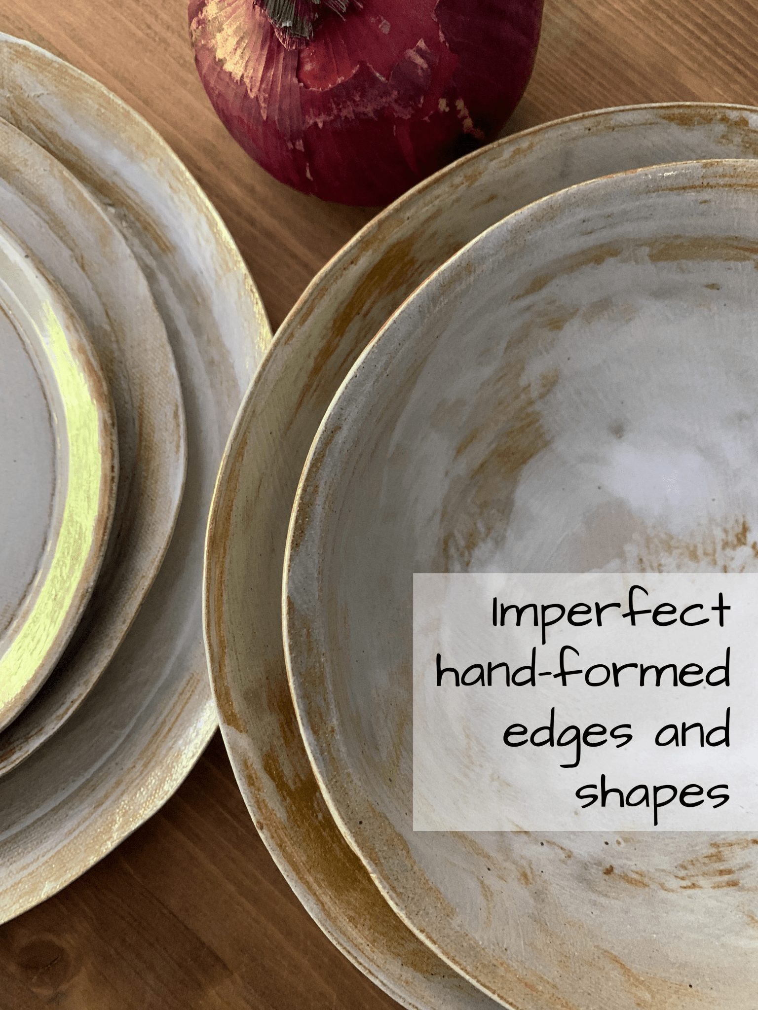 Set of handmade ceramic plates with imperfect edges on a wooden surface