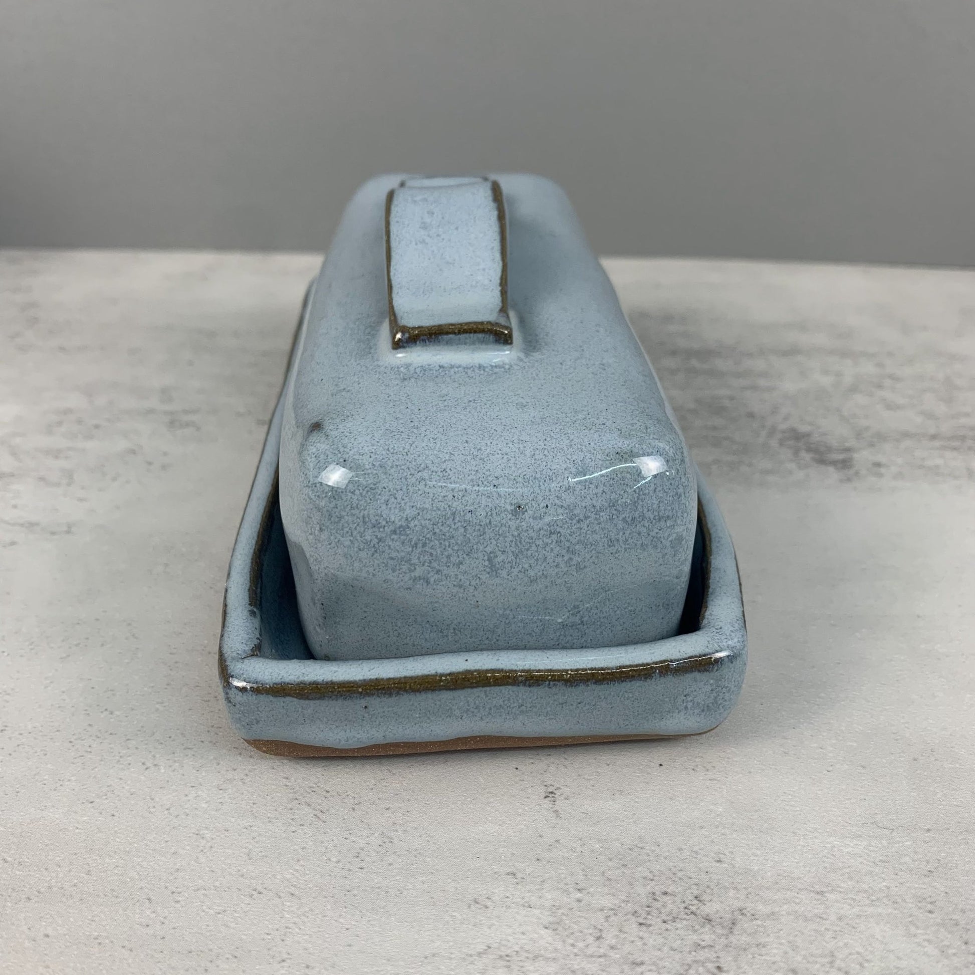 Blue ceramic butter dish on a gray surface with a gray background