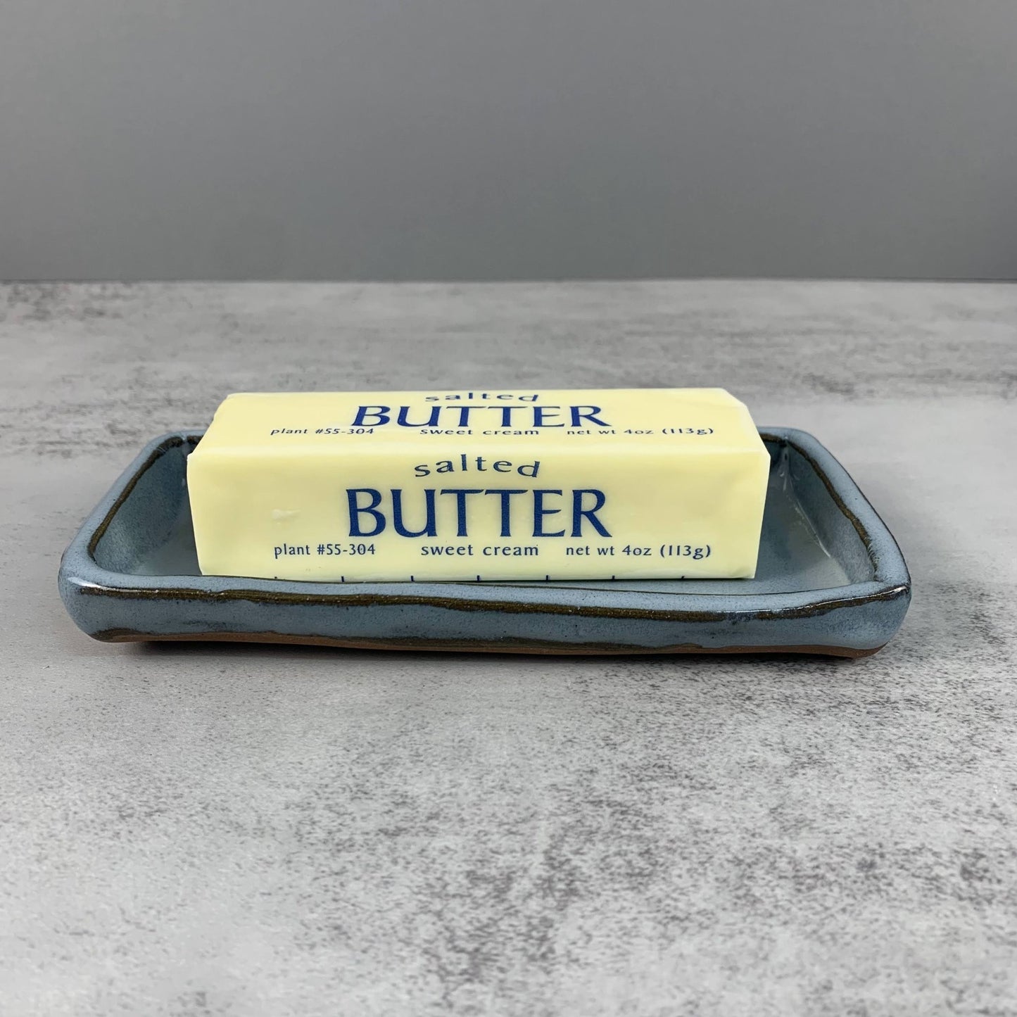 Butter stick on a blue ceramic tray with a gray background