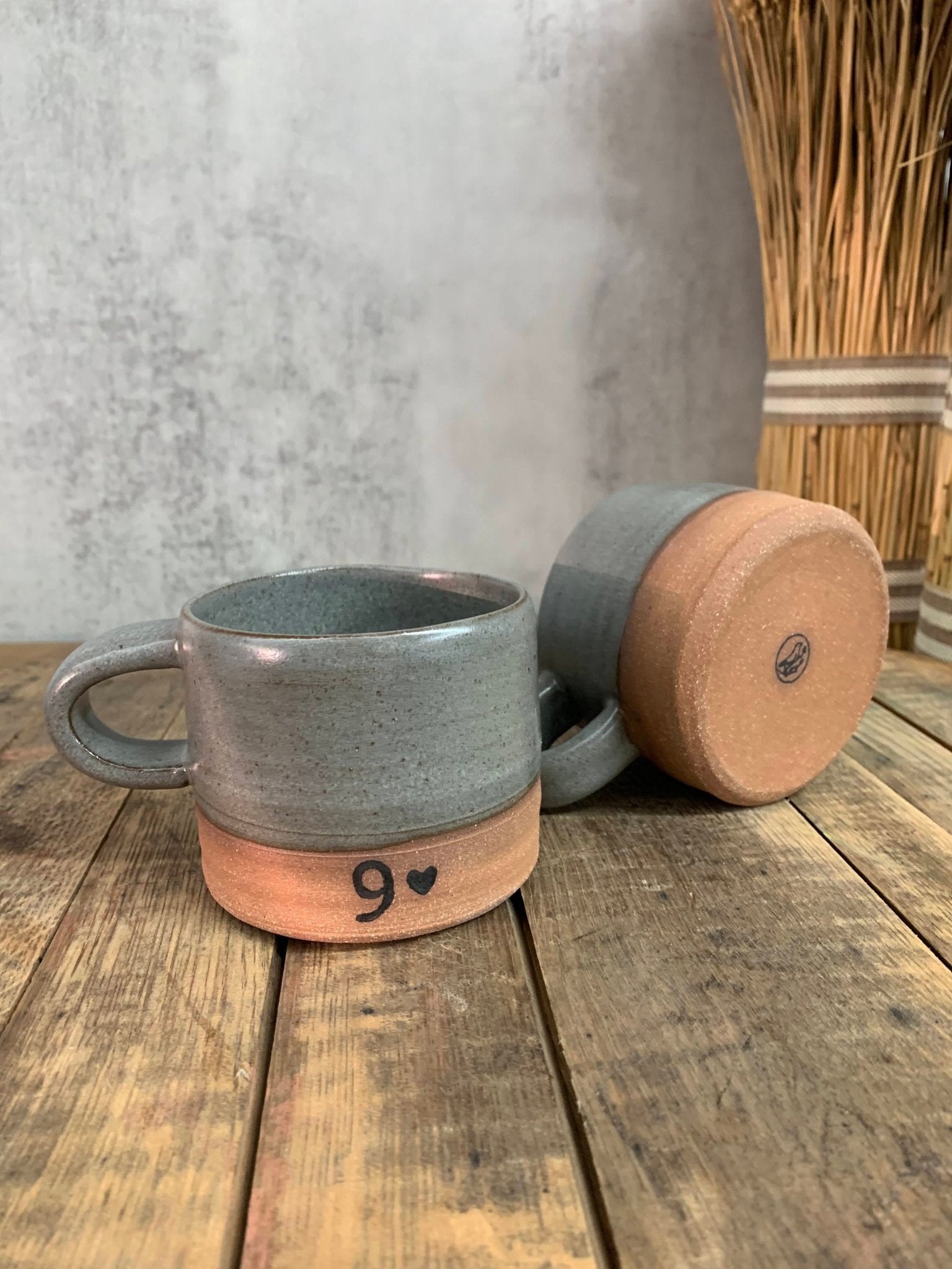 Gray handmade ceramic mug with wooden coaster on a wooden surface