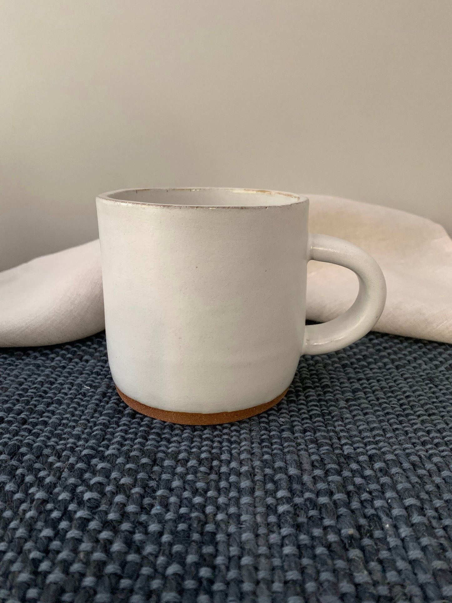 White ceramic mug on a textured surface with a neutral background