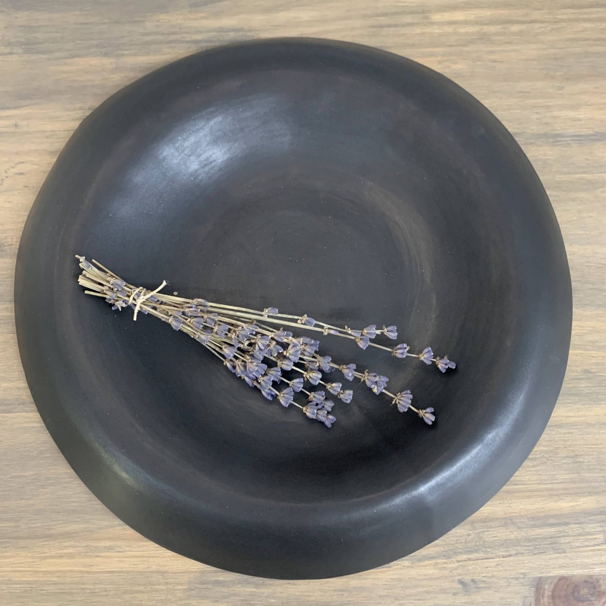 Black bowl with dried lavender on a wooden surface