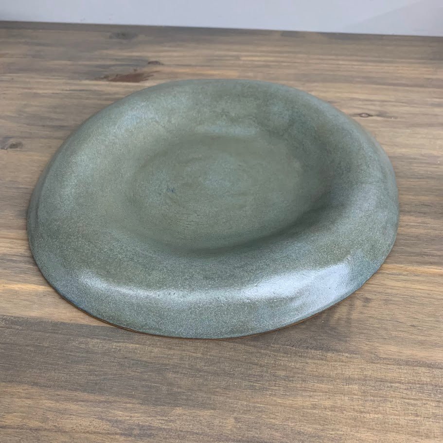 Green ceramic shallow bowl on a wooden surface