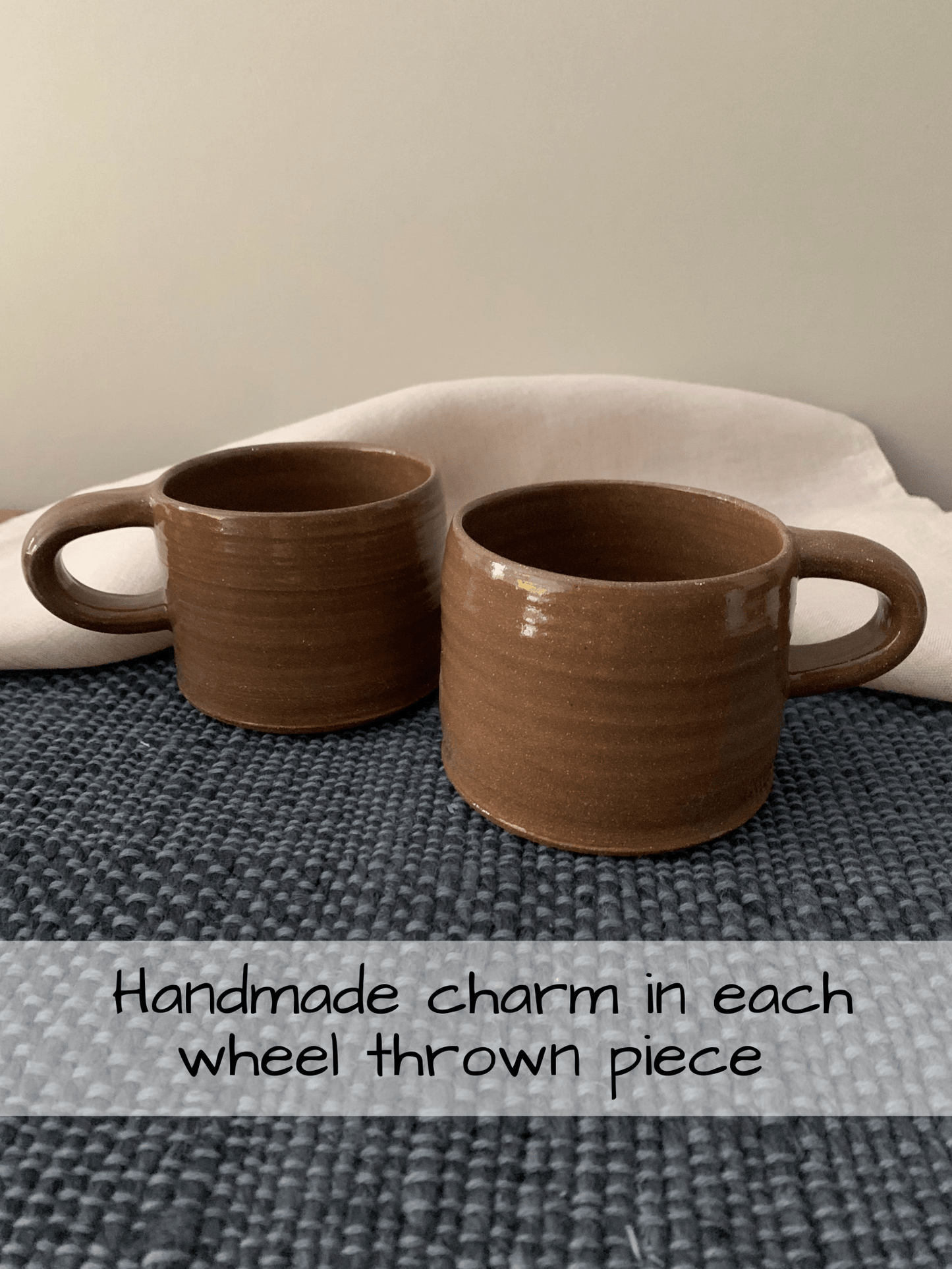 Two brown ceramic mugs on a textured surface with a neutral background