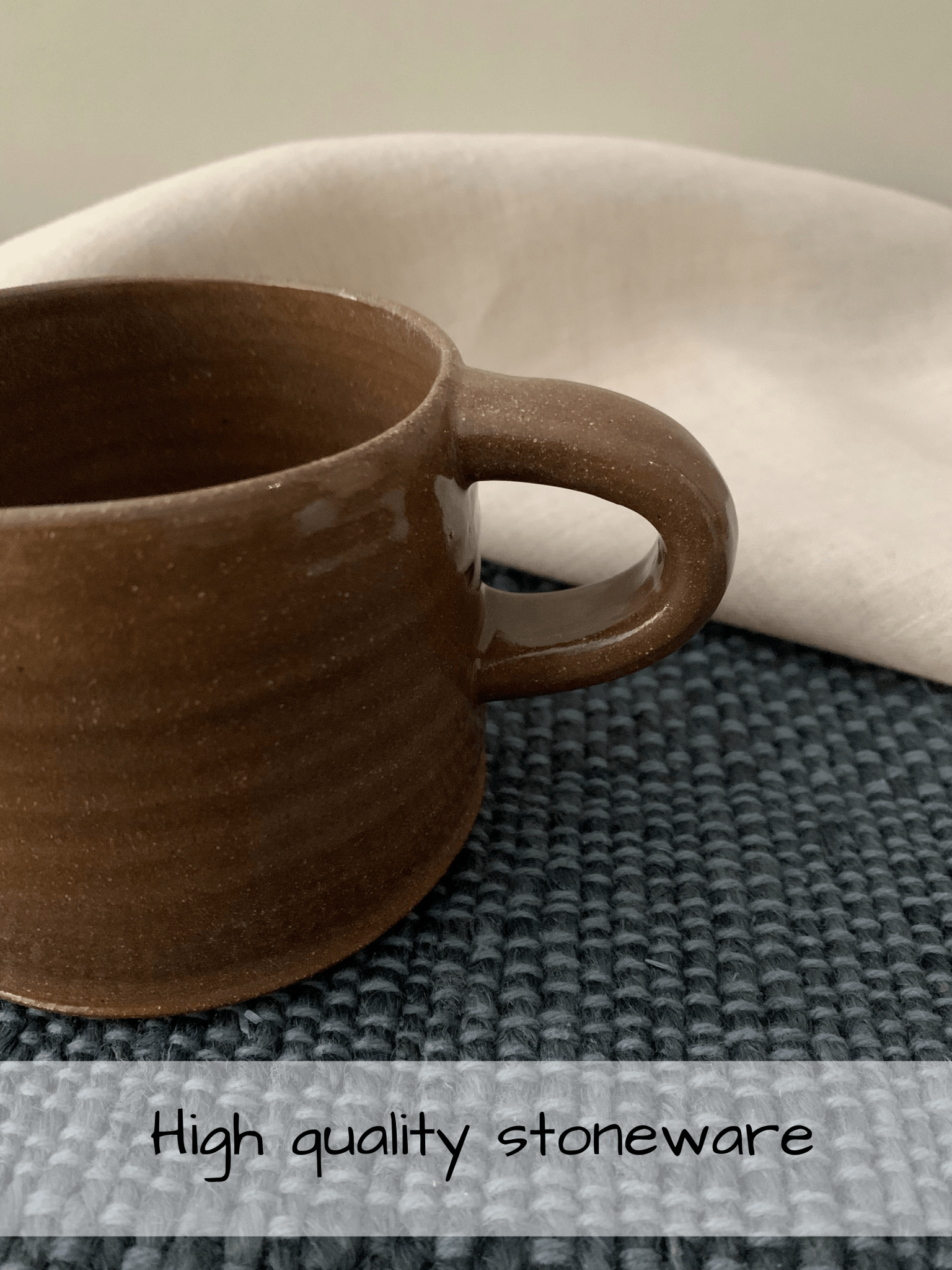 Brown ceramic mug on a textured surface with 'High quality stoneware' text.